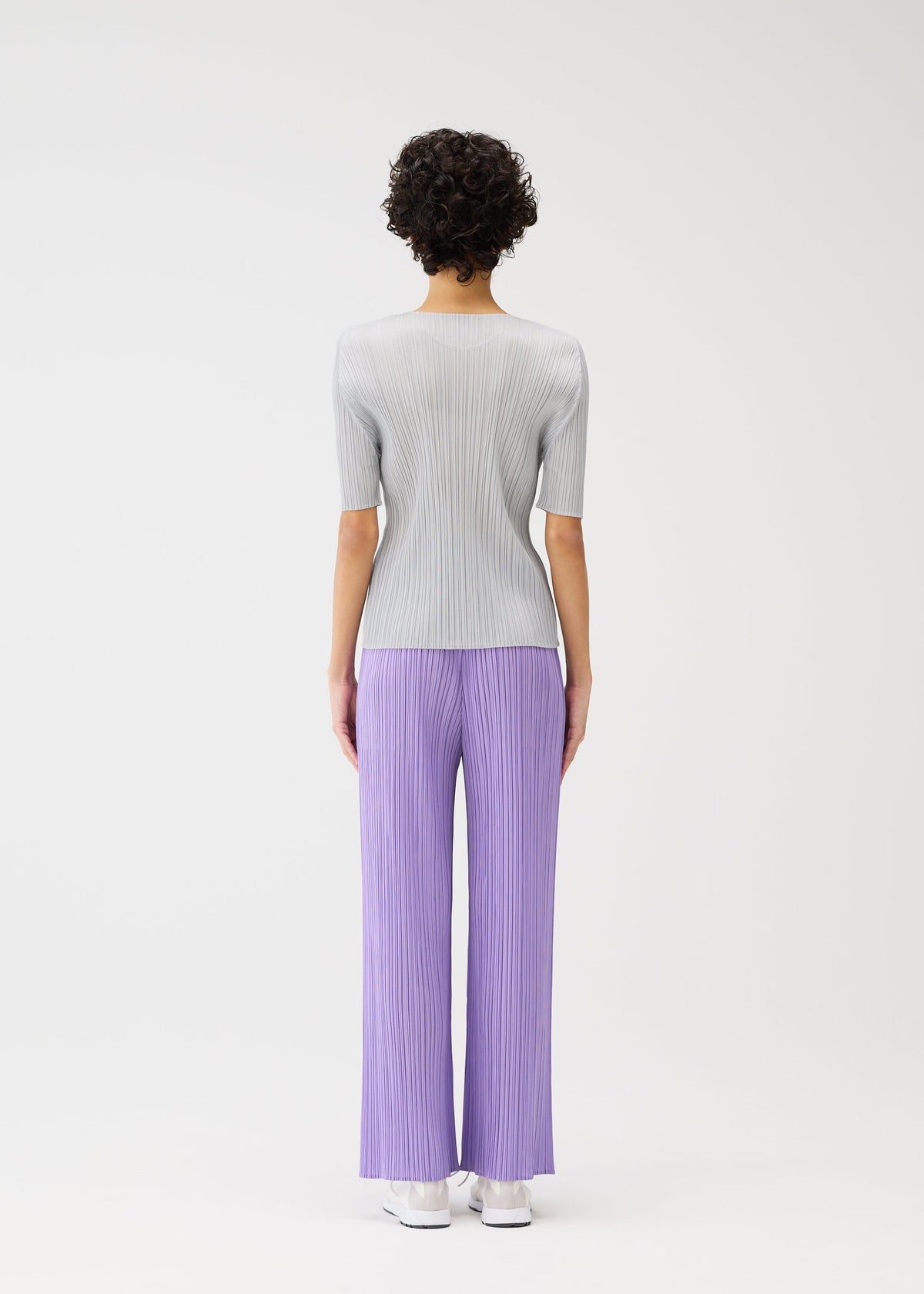 A model wears the PLEATS PLEASE ISSEY MIYAKE MONTHLY COLORS APRIL trousers.