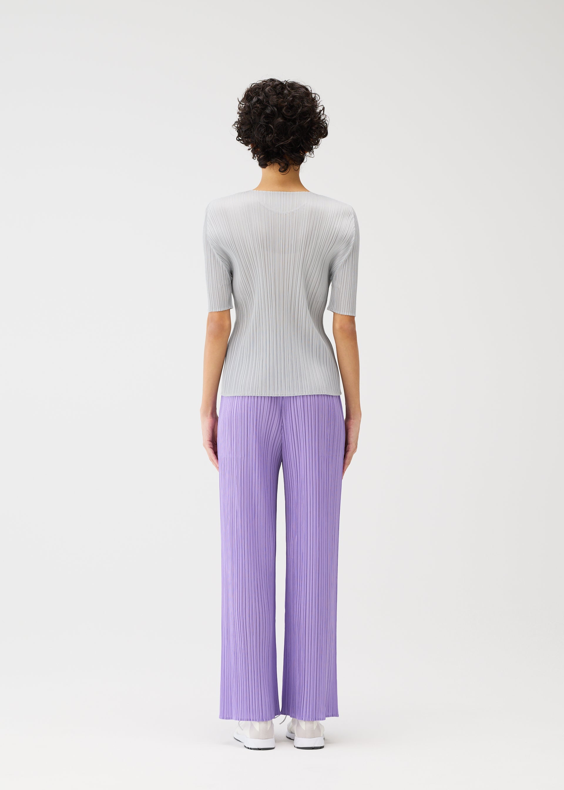 A model wears the PLEATS PLEASE ISSEY MIYAKE MONTHLY COLORS APRIL trousers.