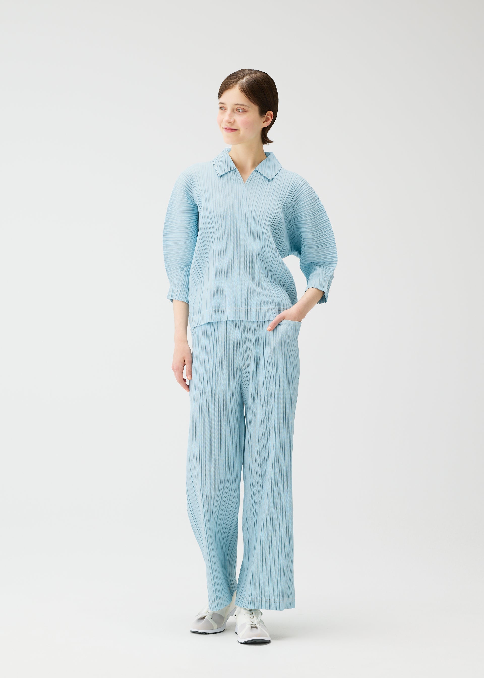 A model wears the PLEATS PLEASE ISSEY MIYAKE COTTON DENIM trousers.