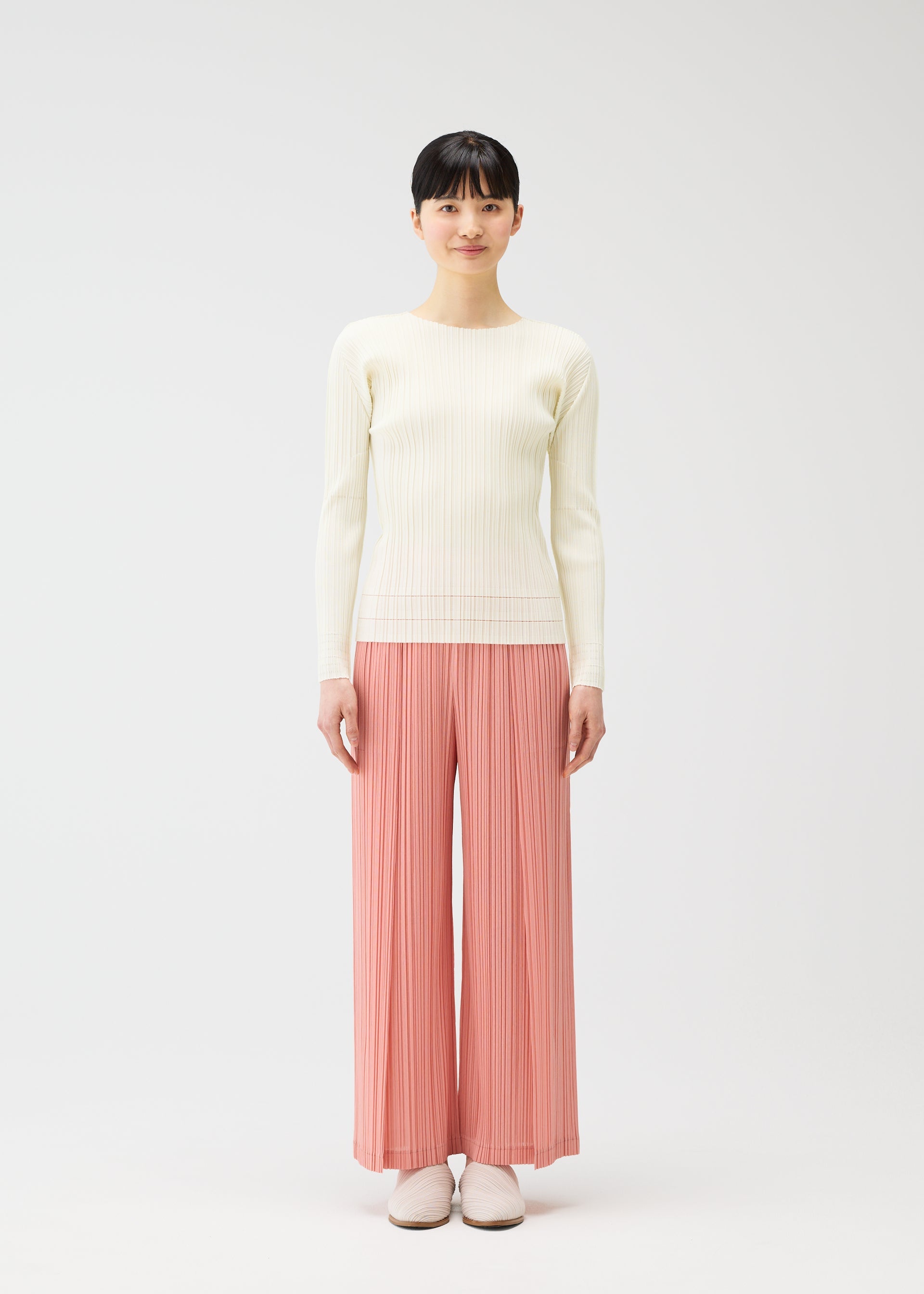 A model wears the PLEATS PLEASE ISSEY MIYAKE RAMIE PLEATS trousers.