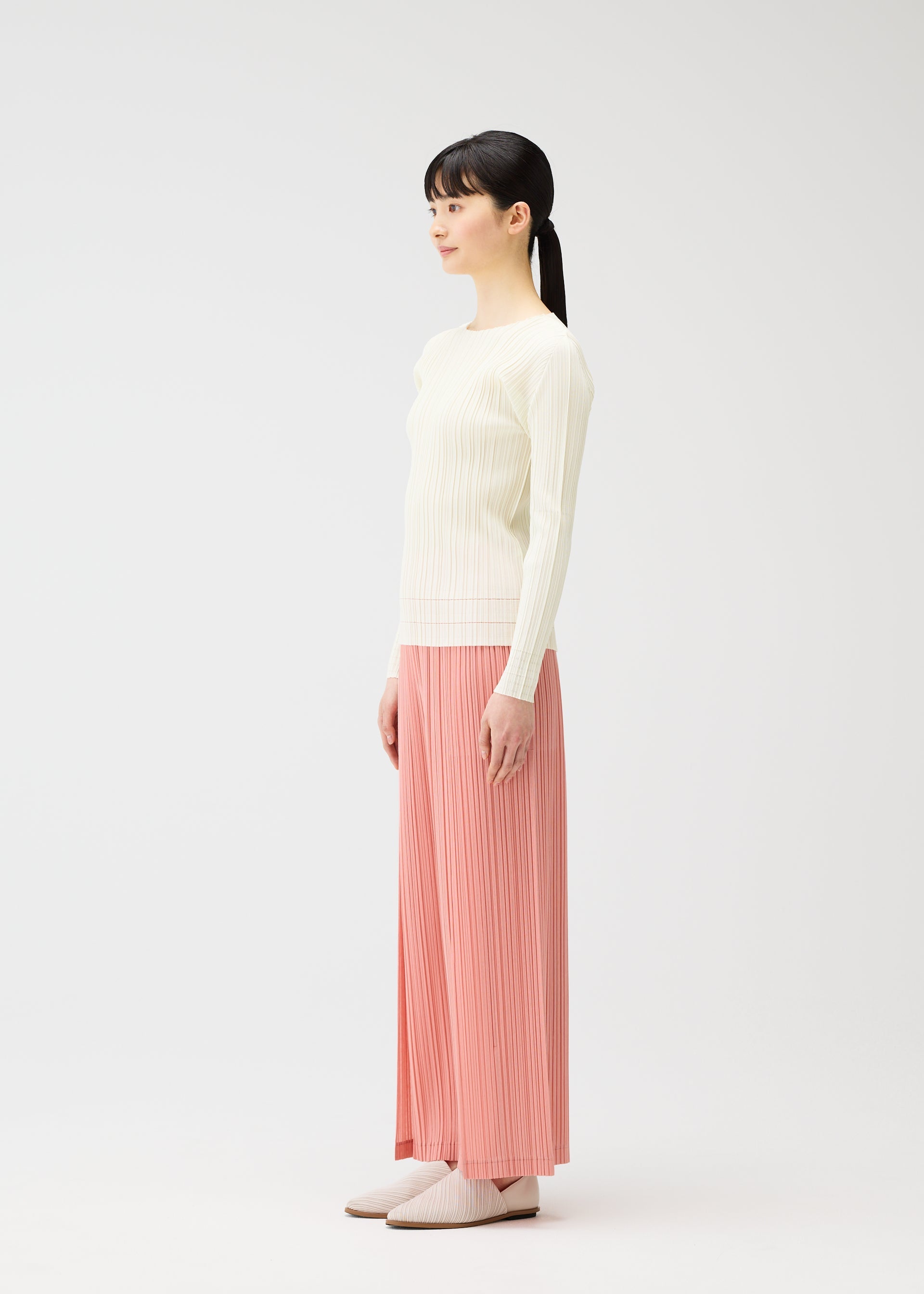A model wears the PLEATS PLEASE ISSEY MIYAKE RAMIE PLEATS trousers.