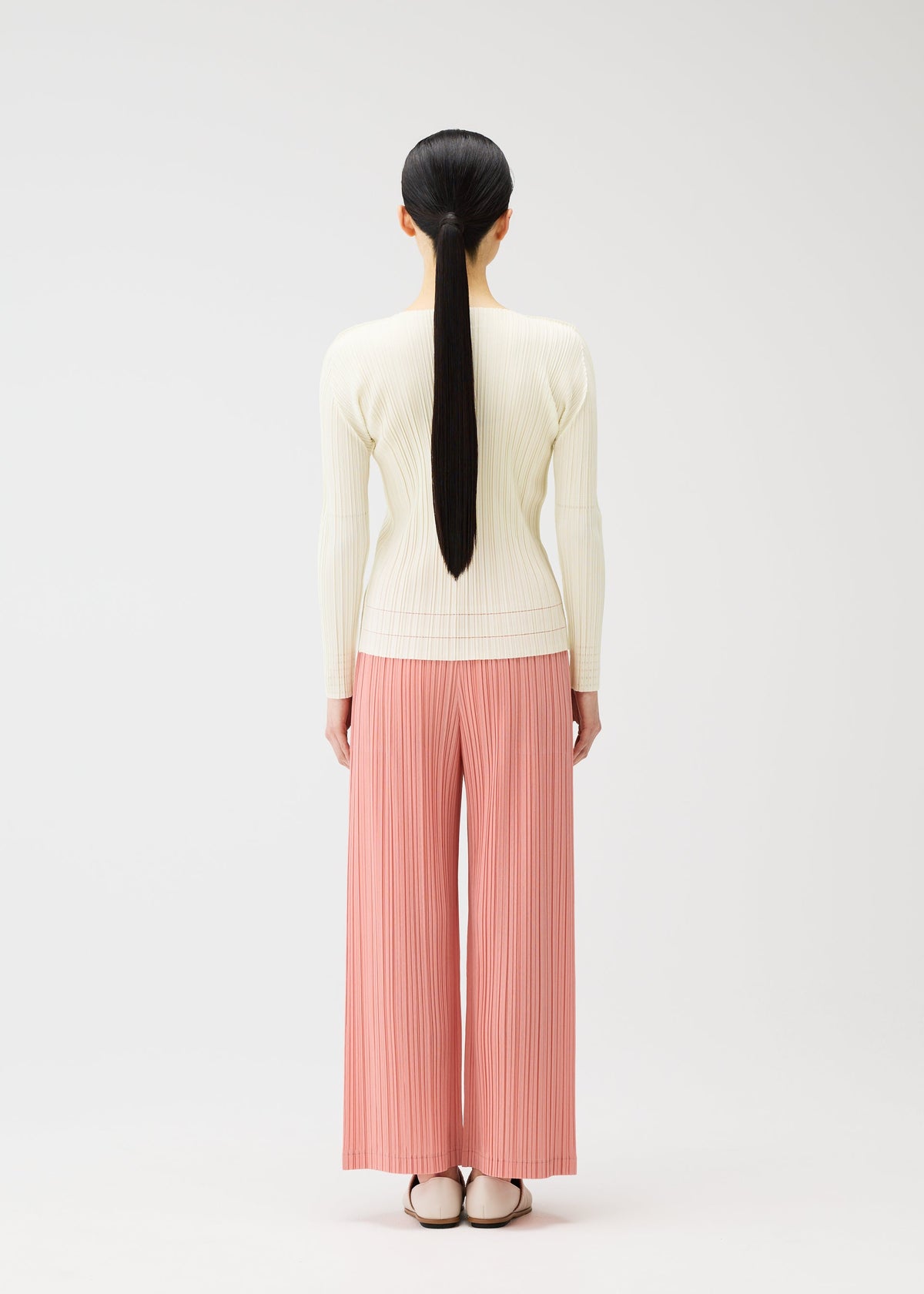 A model wears the PLEATS PLEASE ISSEY MIYAKE RAMIE PLEATS trousers.