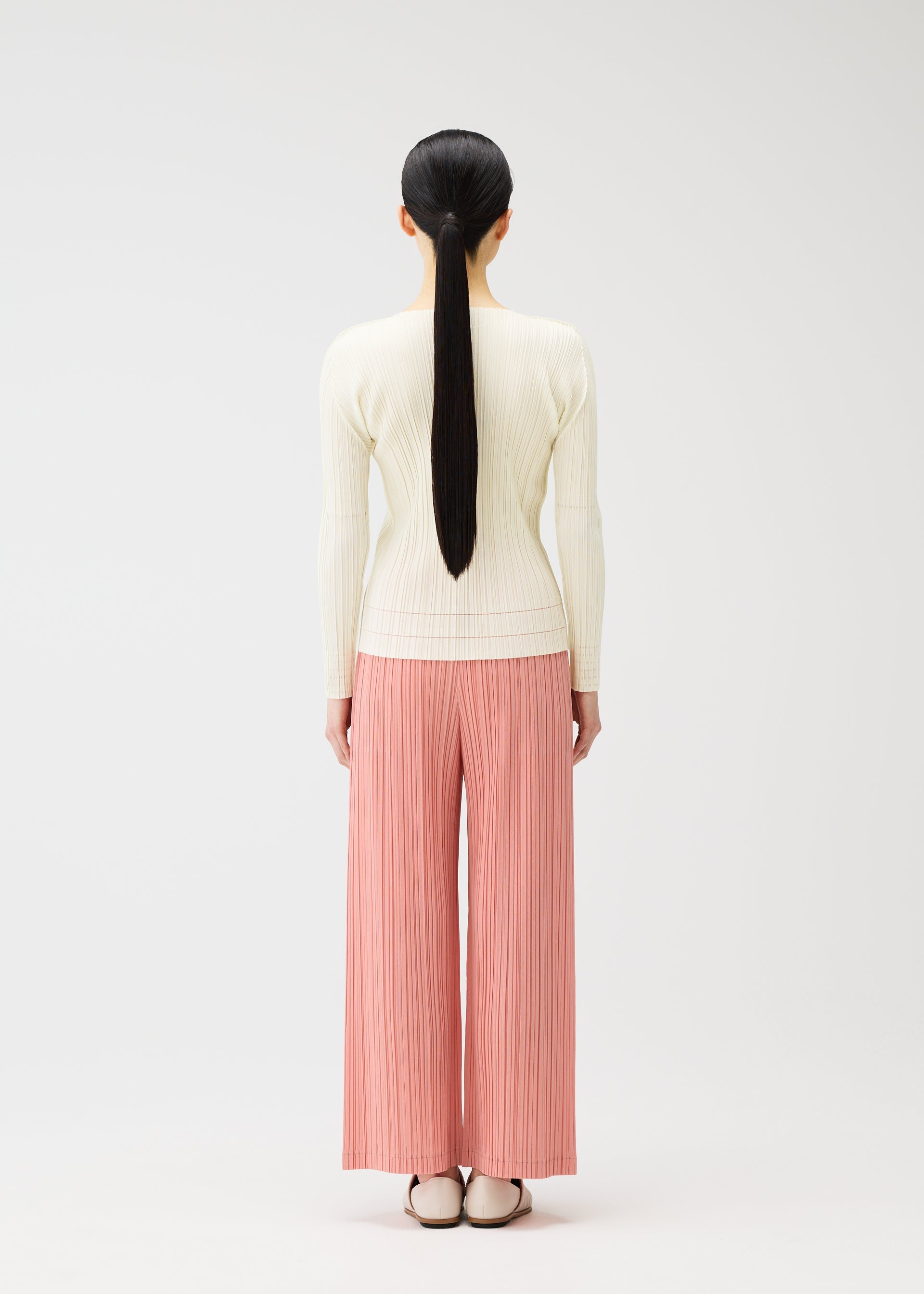 A model wears the PLEATS PLEASE ISSEY MIYAKE RAMIE PLEATS trousers.