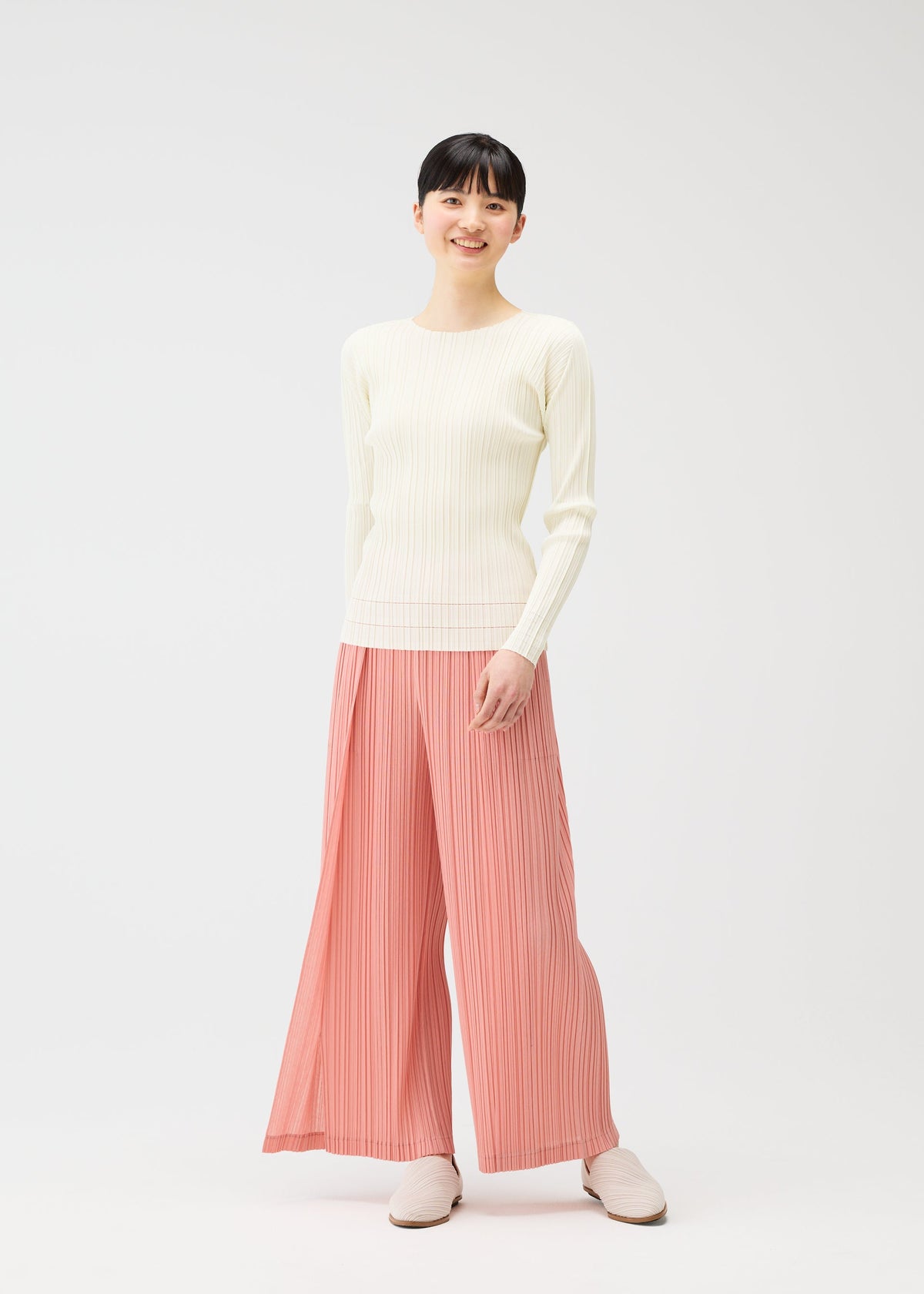 A model wears the PLEATS PLEASE ISSEY MIYAKE RAMIE PLEATS trousers.