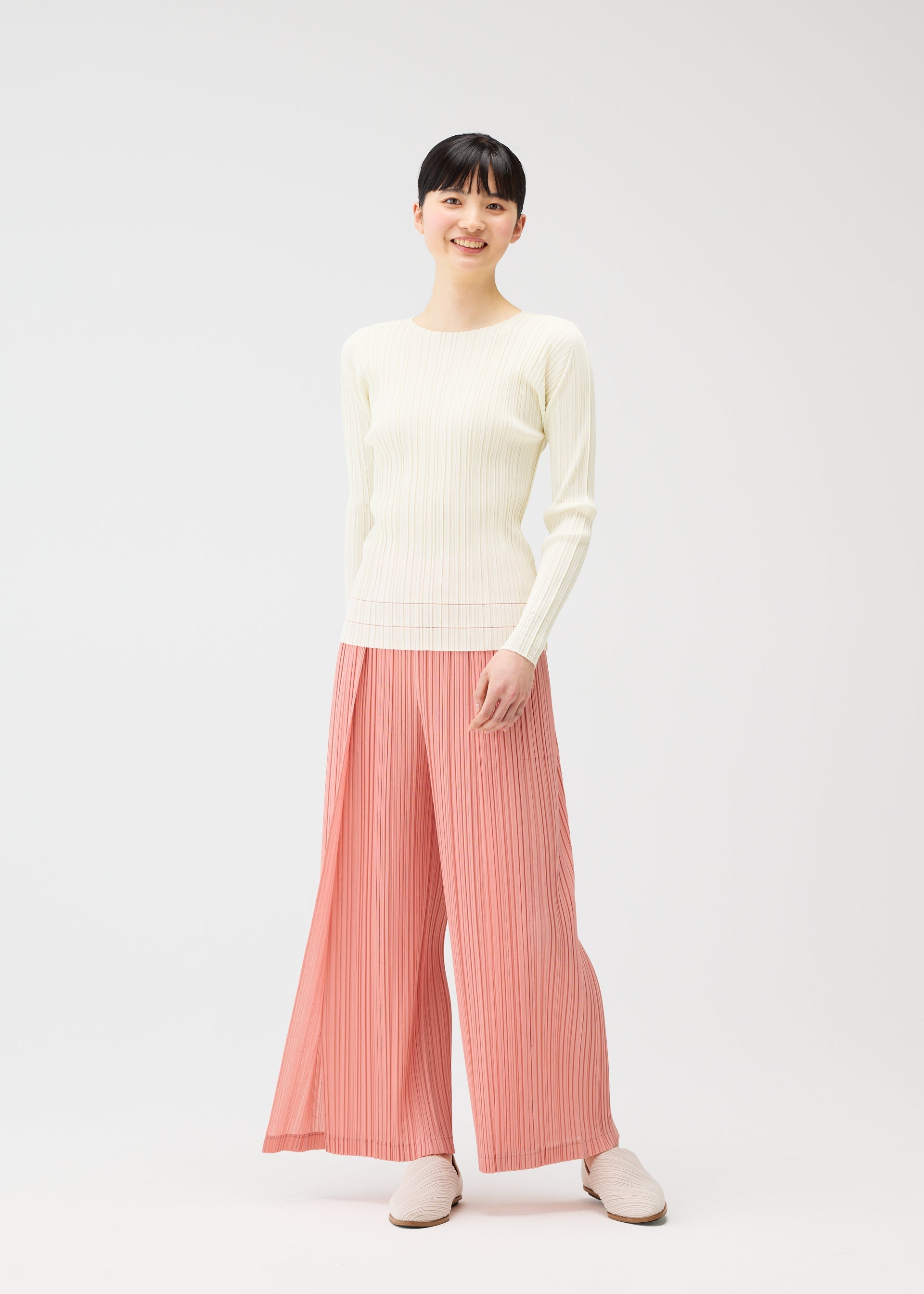 A model wears the PLEATS PLEASE ISSEY MIYAKE RAMIE PLEATS trousers.