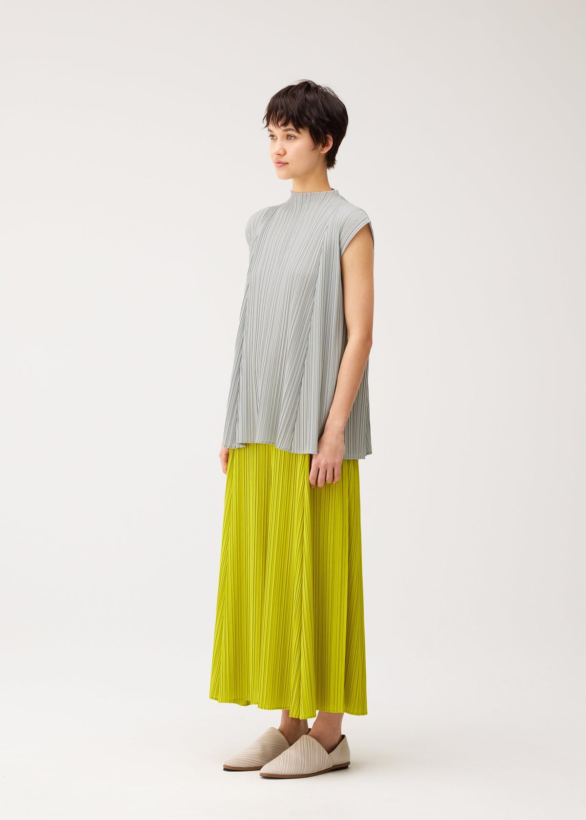 A model wears the PLEATS PLEASE ISSEY MIYAKE MELLOW PLEATS trousers.