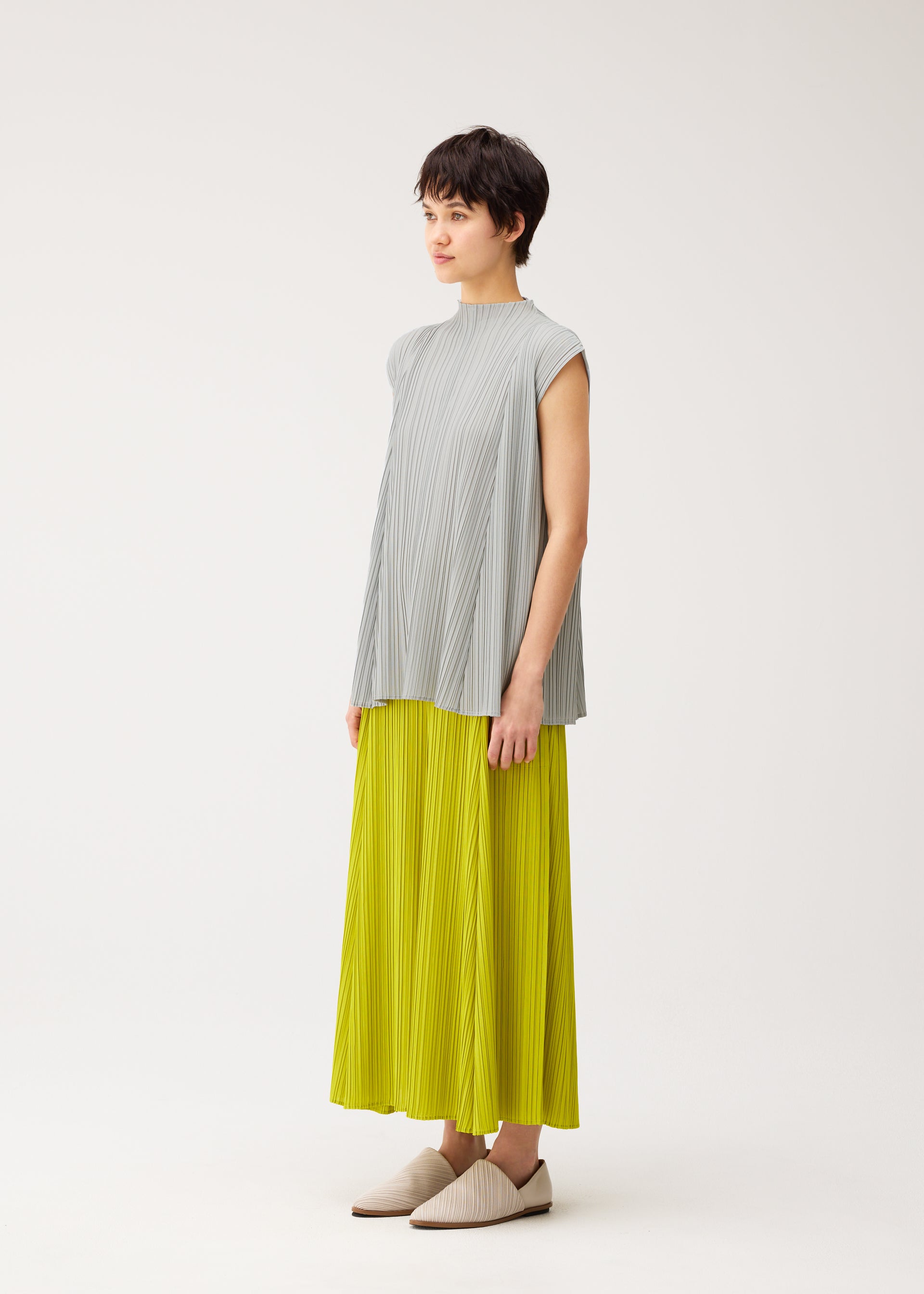 A model wears the PLEATS PLEASE ISSEY MIYAKE MELLOW PLEATS trousers.