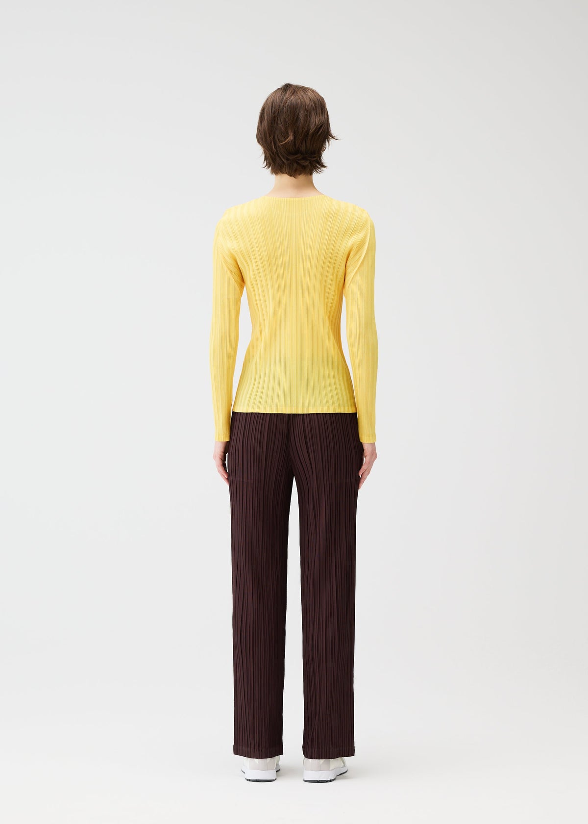 A model wears the PLEATS PLEASE ISSEY MIYAKE THICKER BOTTOMS 1 clothing.