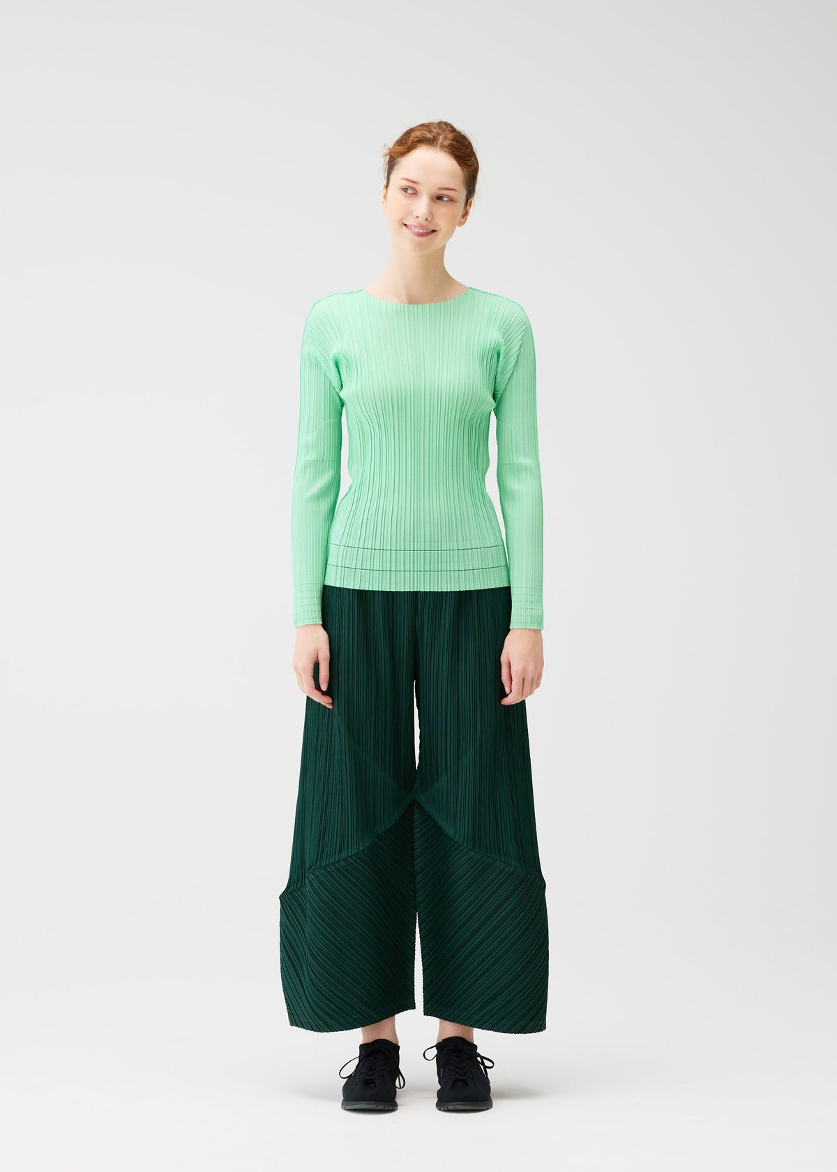 A model wears the PLEATS PLEASE ISSEY MIYAKE THICKER BOTTOMS 2 trousers.