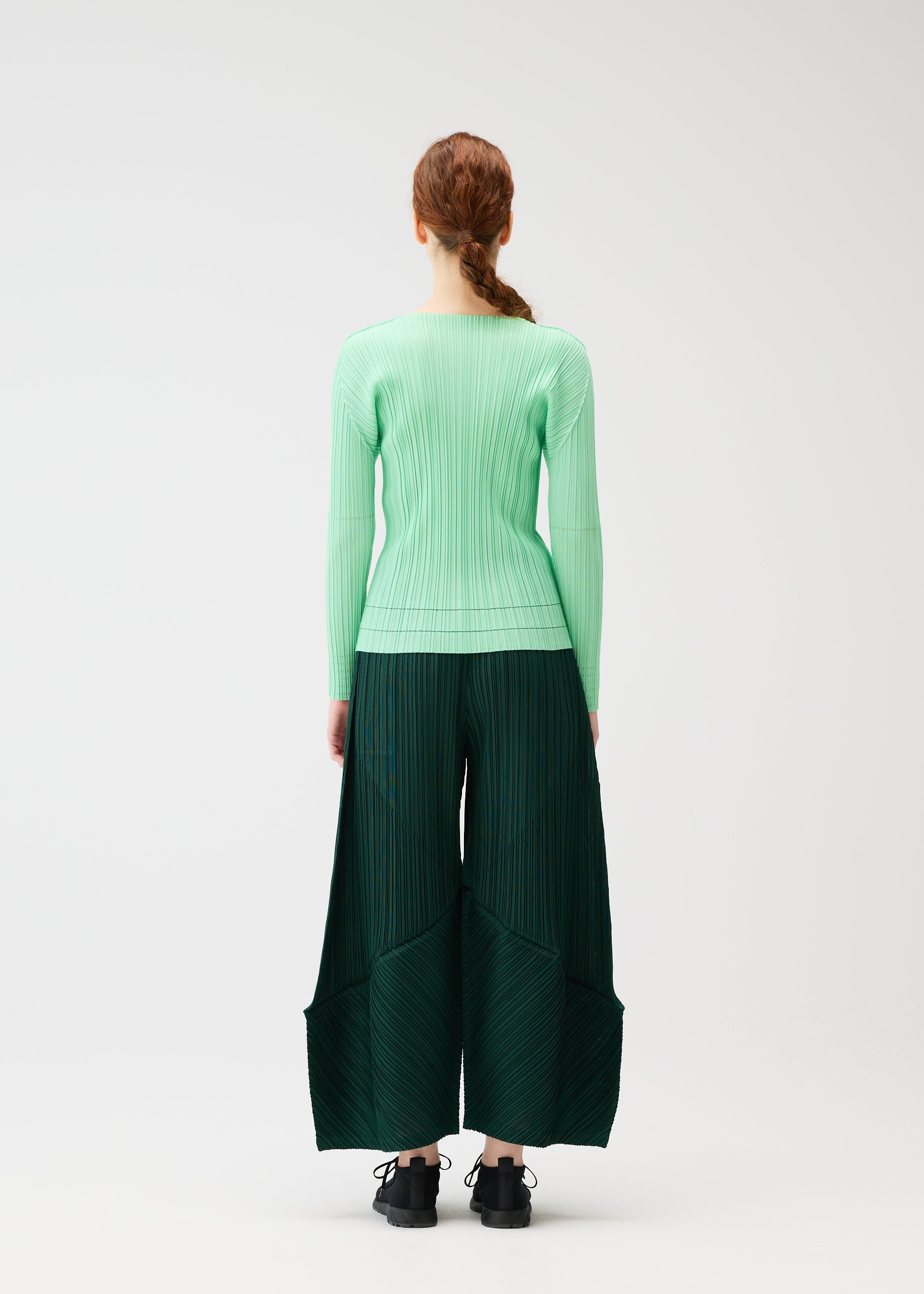 A model wears the PLEATS PLEASE ISSEY MIYAKE THICKER BOTTOMS 2 trousers.