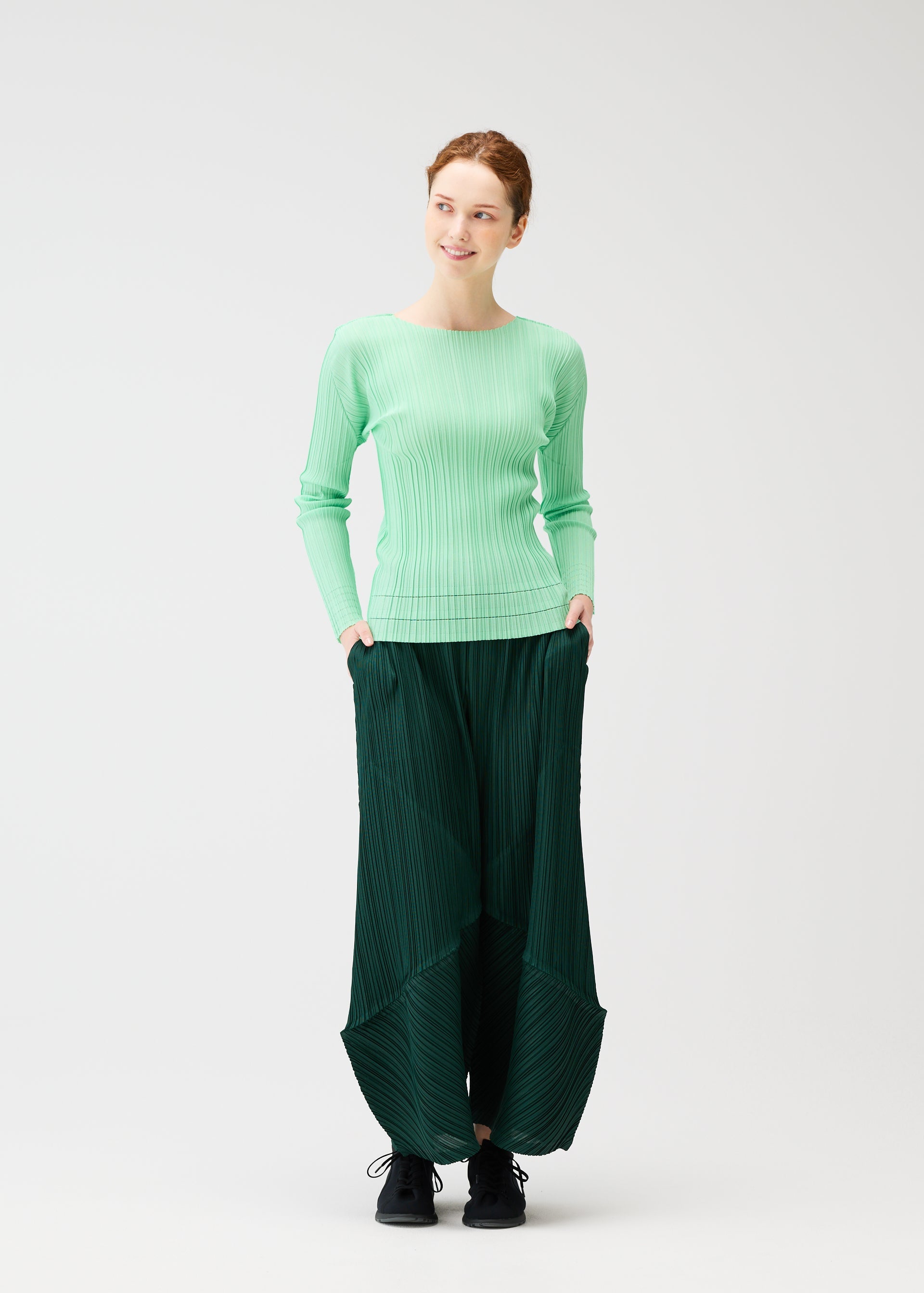 A model wears the PLEATS PLEASE ISSEY MIYAKE THICKER BOTTOMS 2 trousers.