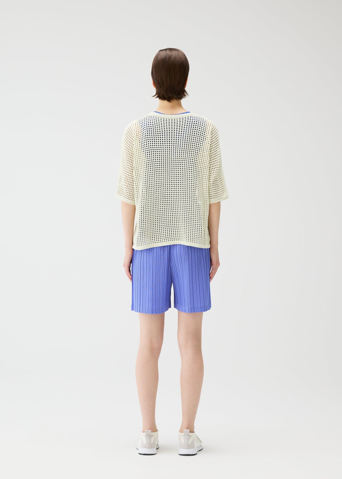 A model wears the PLEATS PLEASE ISSEY MIYAKE LOOP BOTTOMS shorts.