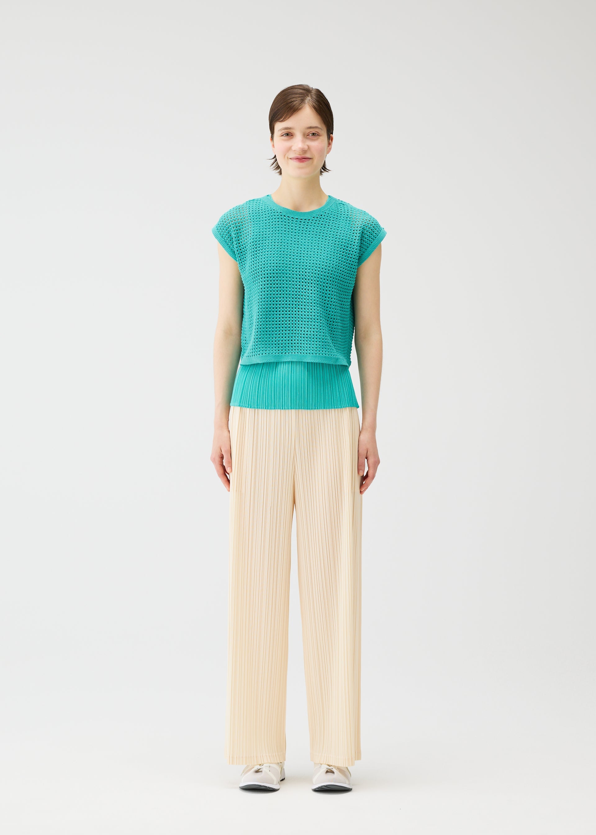 A model wears the PLEATS PLEASE ISSEY MIYAKE LOOP BOTTOMS trousers.