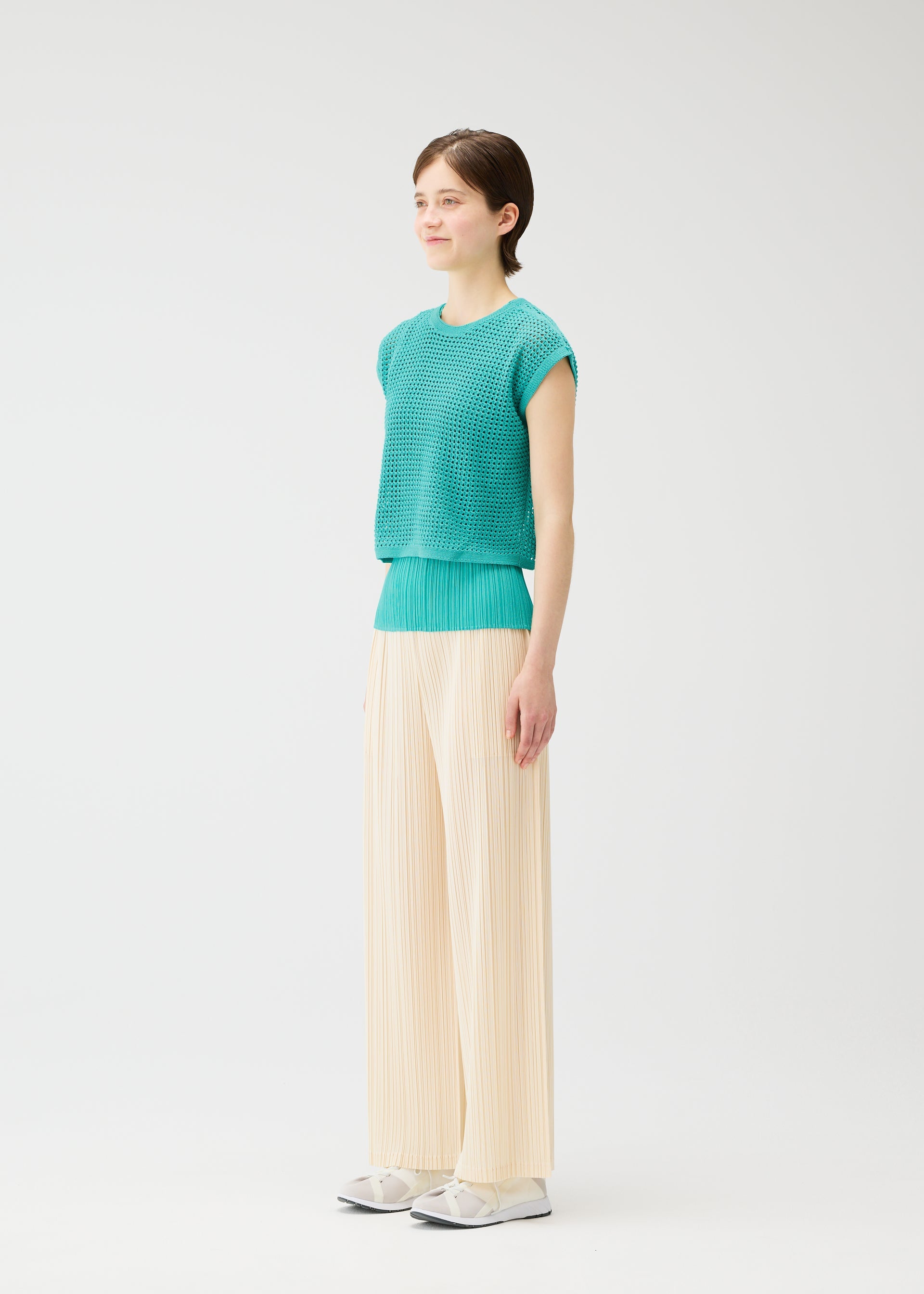 A model wears the PLEATS PLEASE ISSEY MIYAKE LOOP BOTTOMS trousers.