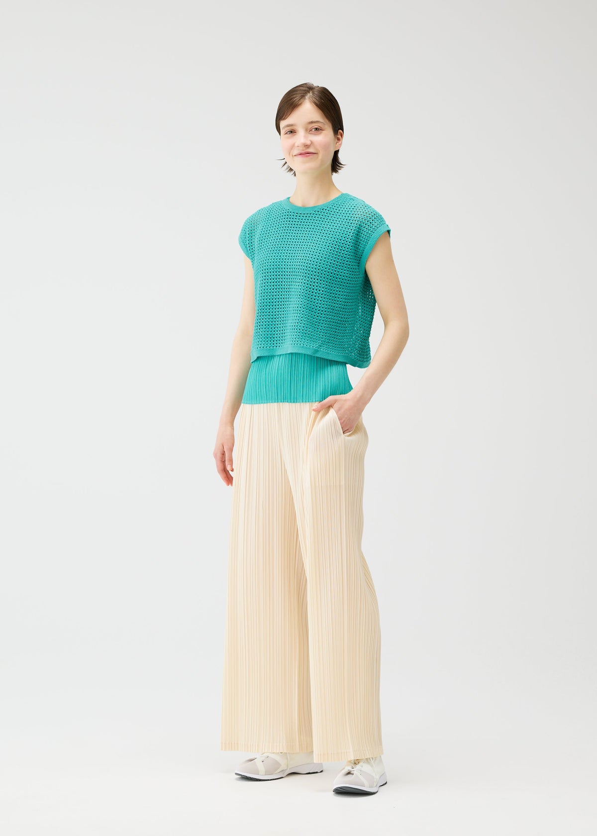 A model wears the PLEATS PLEASE ISSEY MIYAKE LOOP BOTTOMS trousers.