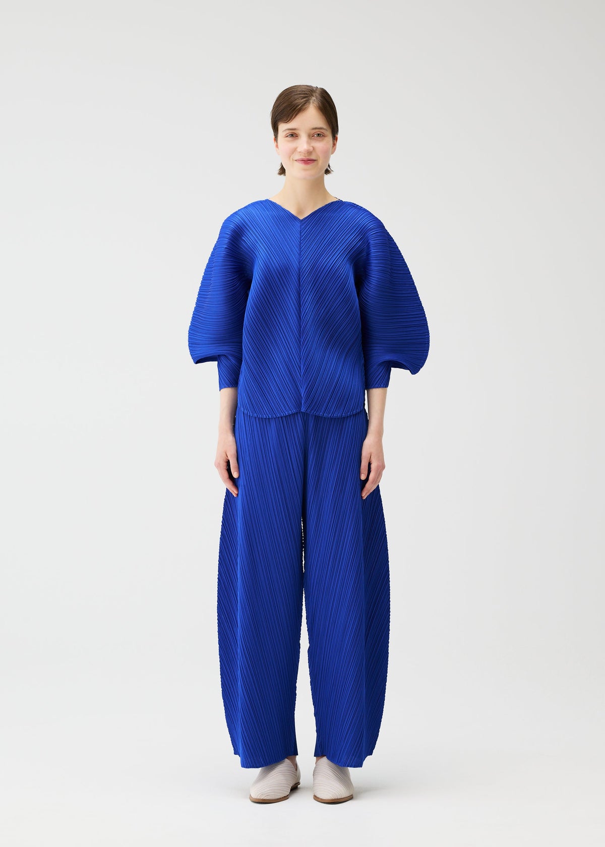 A model wears the PLEATS PLEASE ISSEY MIYAKE COAST trousers.