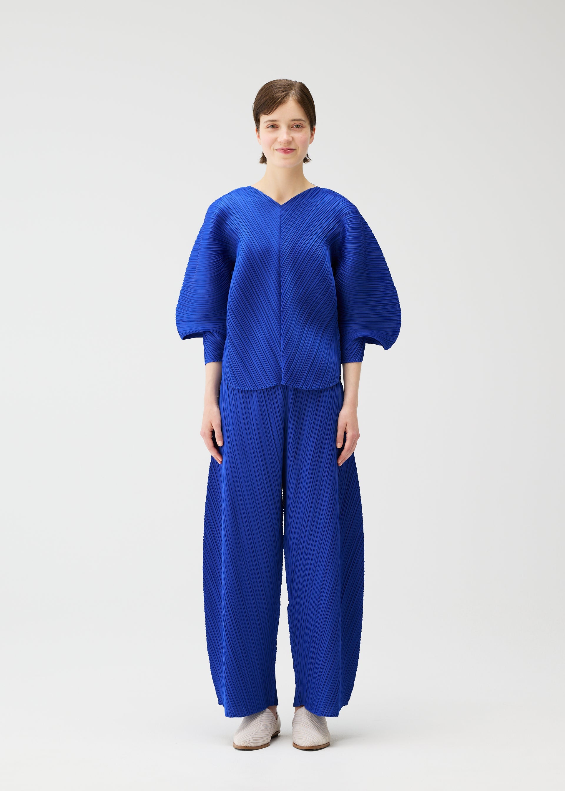A model wears the PLEATS PLEASE ISSEY MIYAKE COAST trousers.