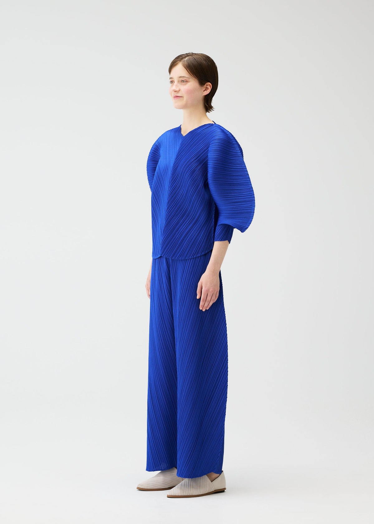 A model wears the PLEATS PLEASE ISSEY MIYAKE COAST trousers.