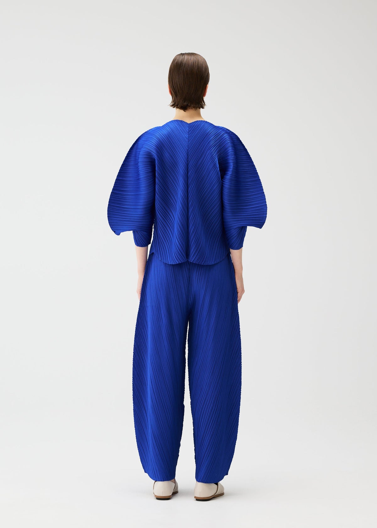 A model wears the PLEATS PLEASE ISSEY MIYAKE COAST trousers.