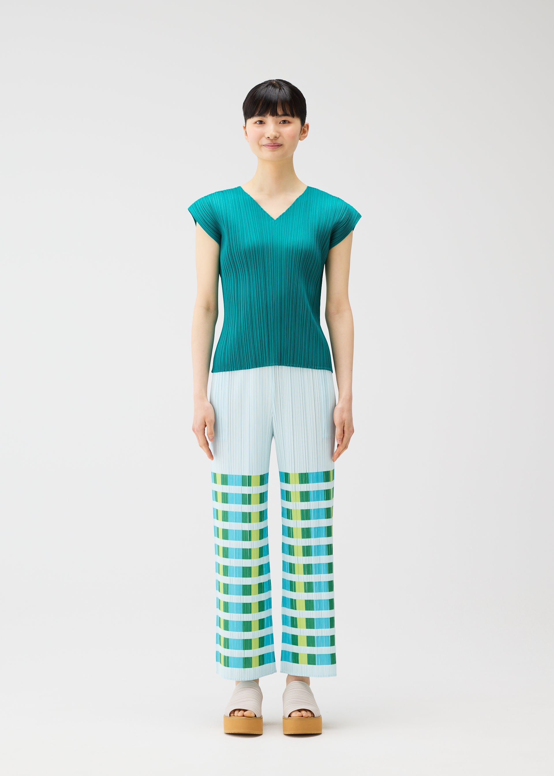 A model wears the PLEATS PLEASE ISSEY MIYAKE BUMPY BASKET bumpy-basket-trousers-charcoal.