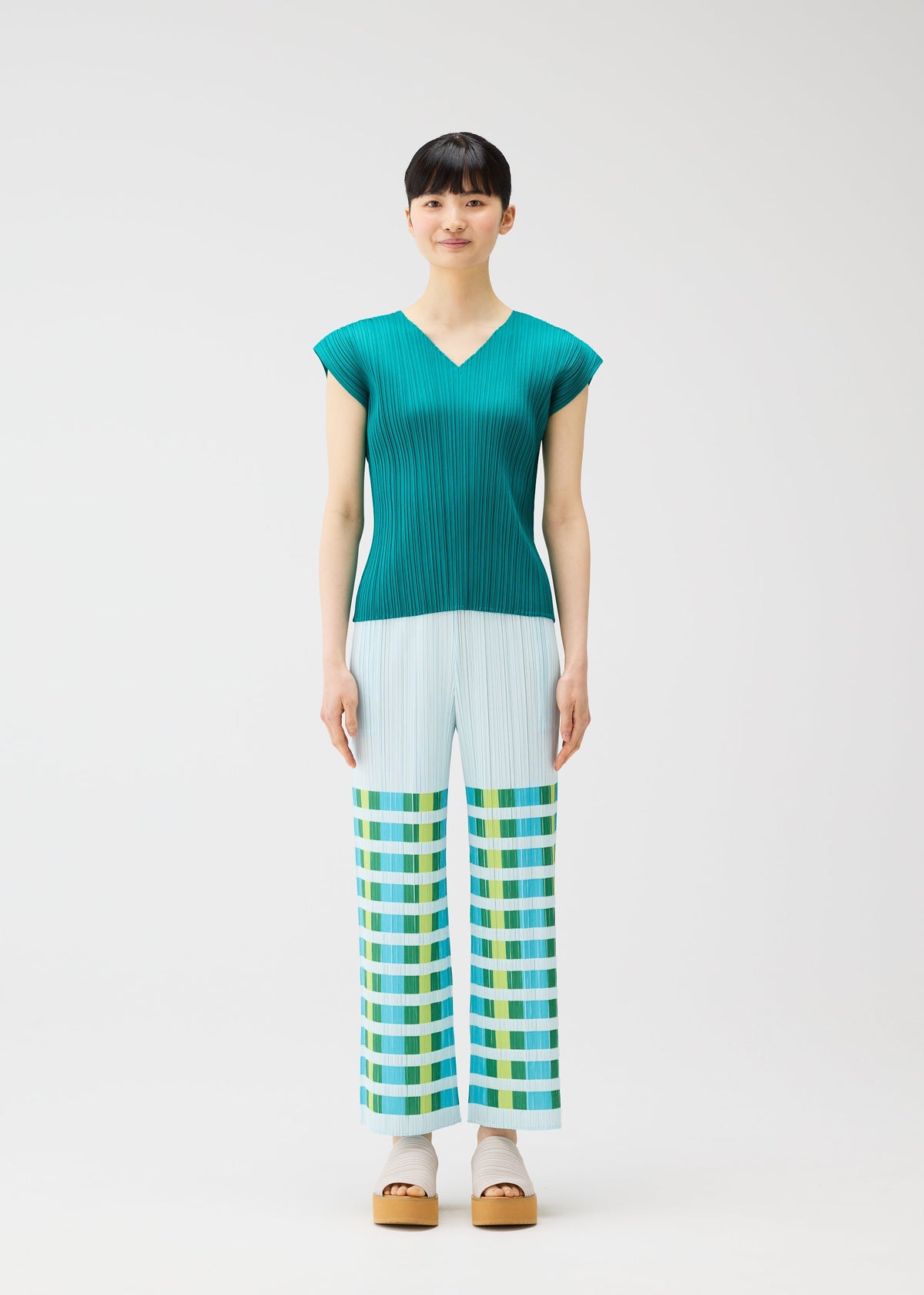 A model wears the PLEATS PLEASE ISSEY MIYAKE BUMPY BASKET bumpy-basket-trousers-green.