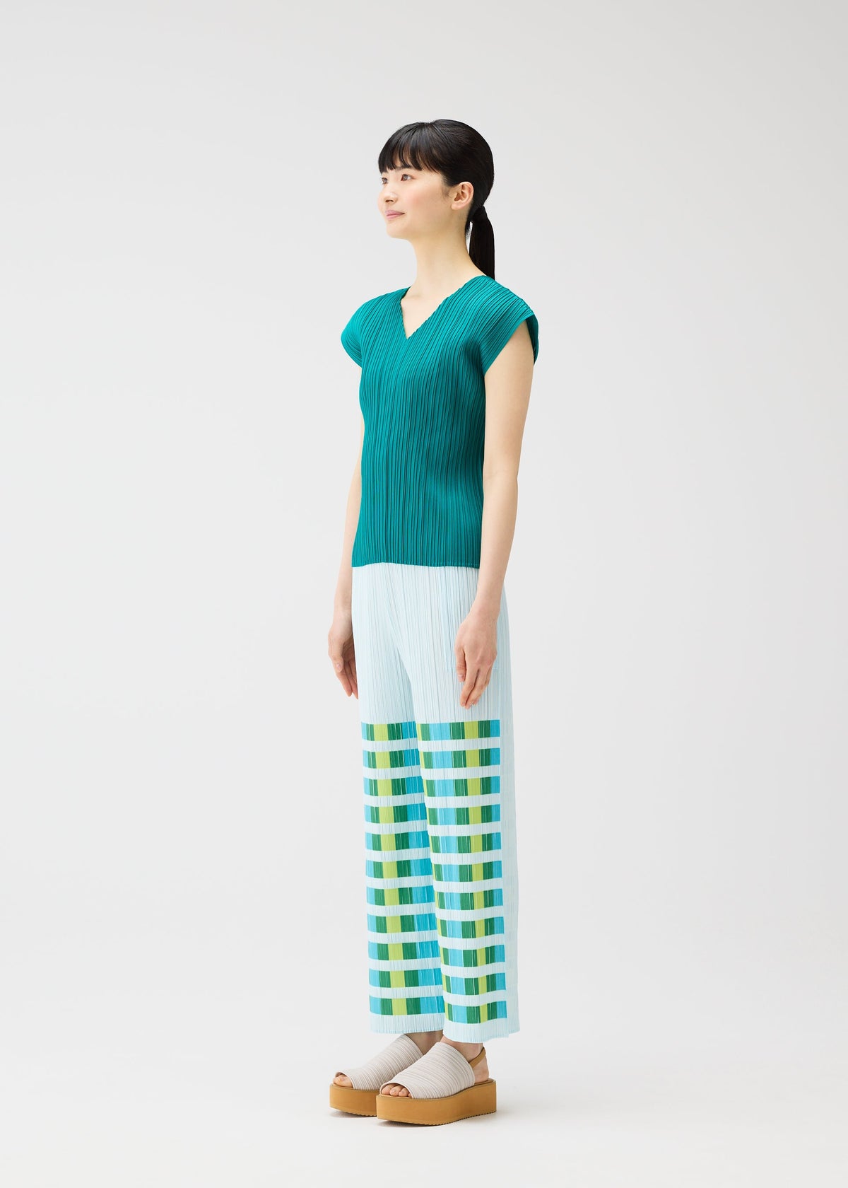 A model wears the PLEATS PLEASE ISSEY MIYAKE BUMPY BASKET bumpy-basket-trousers-pink.