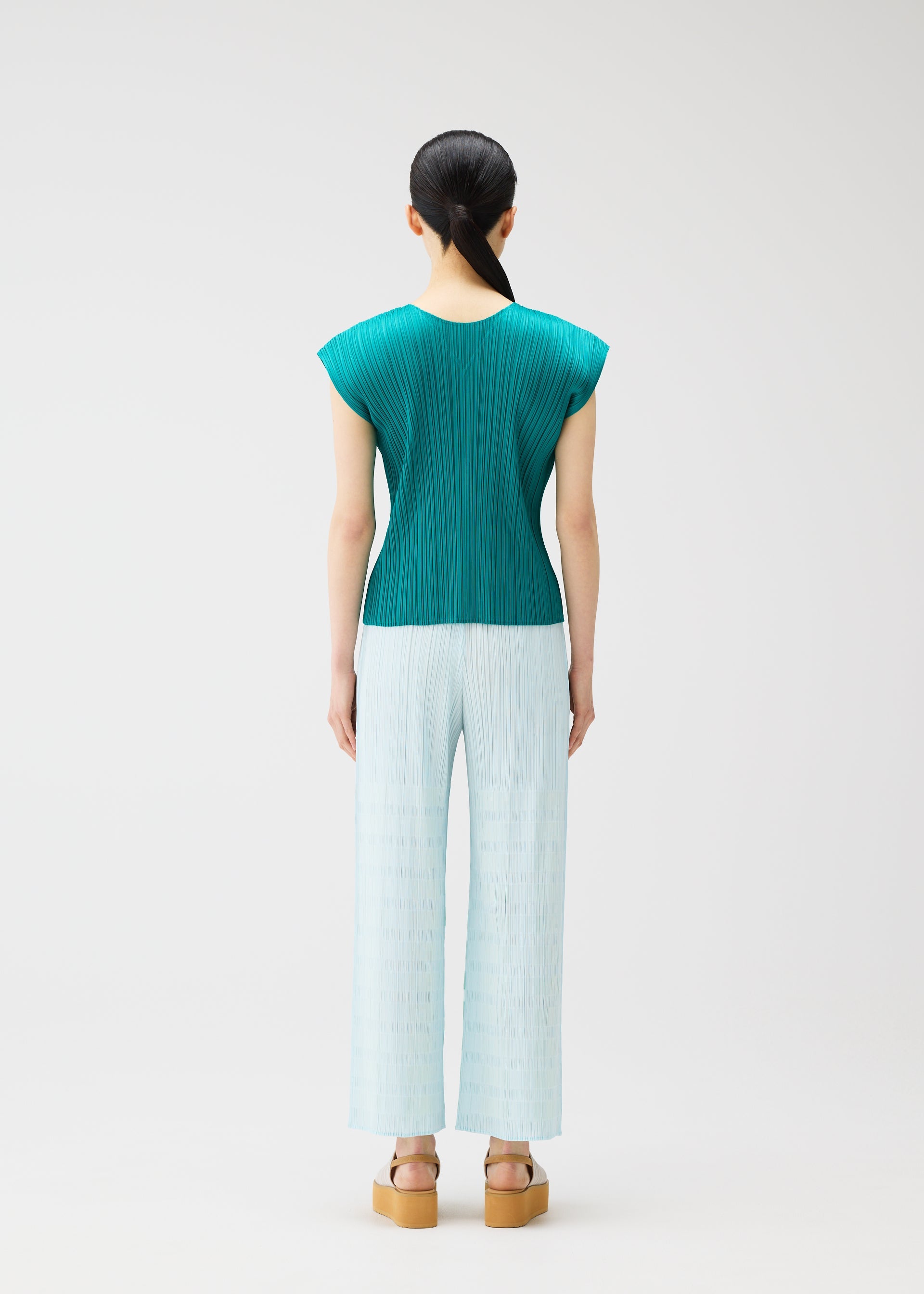 A model wears the PLEATS PLEASE ISSEY MIYAKE BUMPY BASKET bumpy-basket-trousers-charcoal.