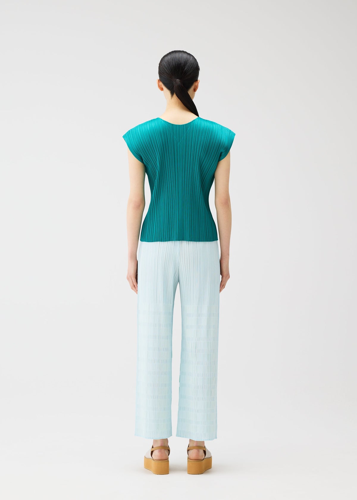 A model wears the PLEATS PLEASE ISSEY MIYAKE BUMPY BASKET bumpy-basket-trousers-pink.