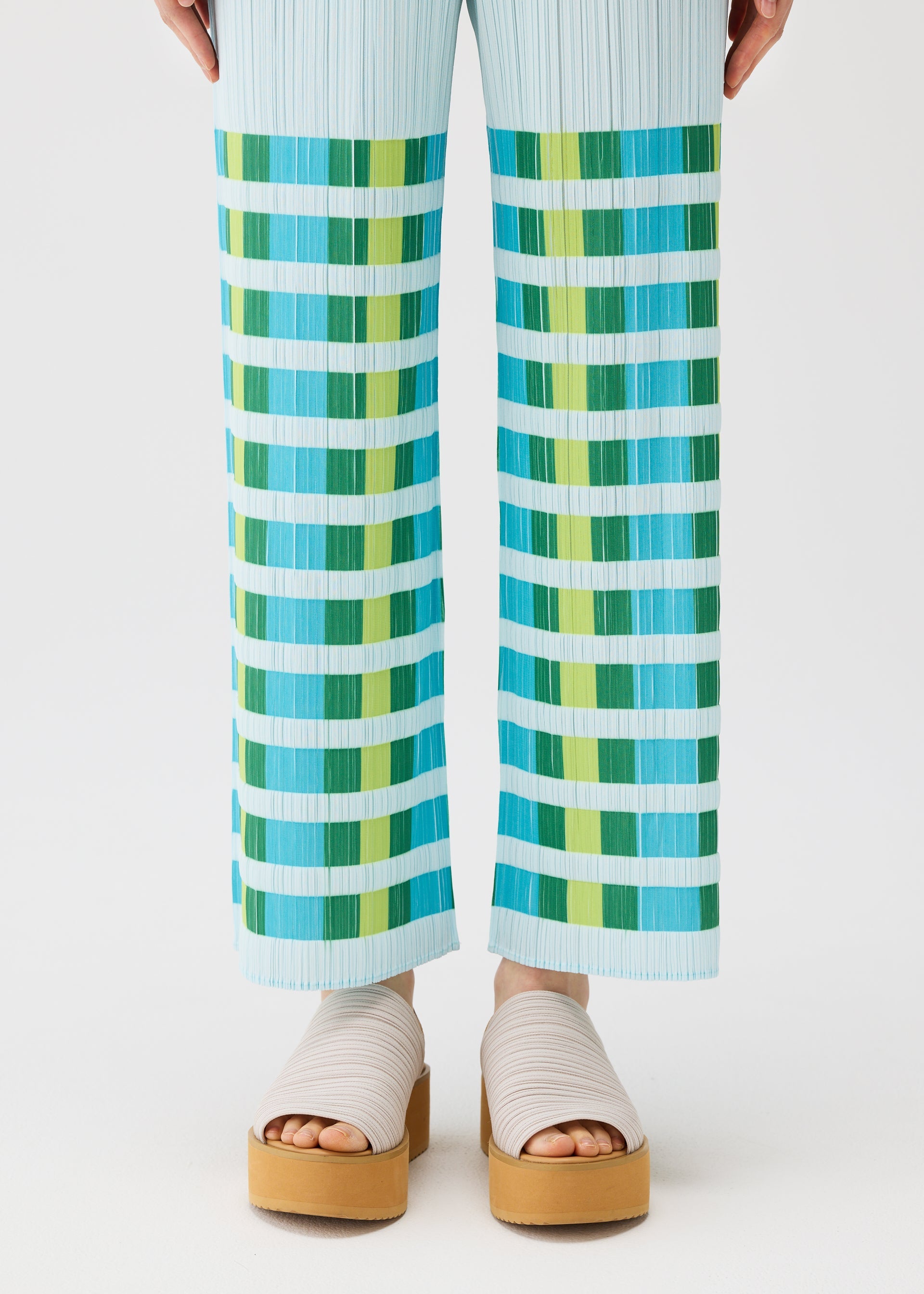 A model wears the PLEATS PLEASE ISSEY MIYAKE BUMPY BASKET bumpy-basket-trousers-green.