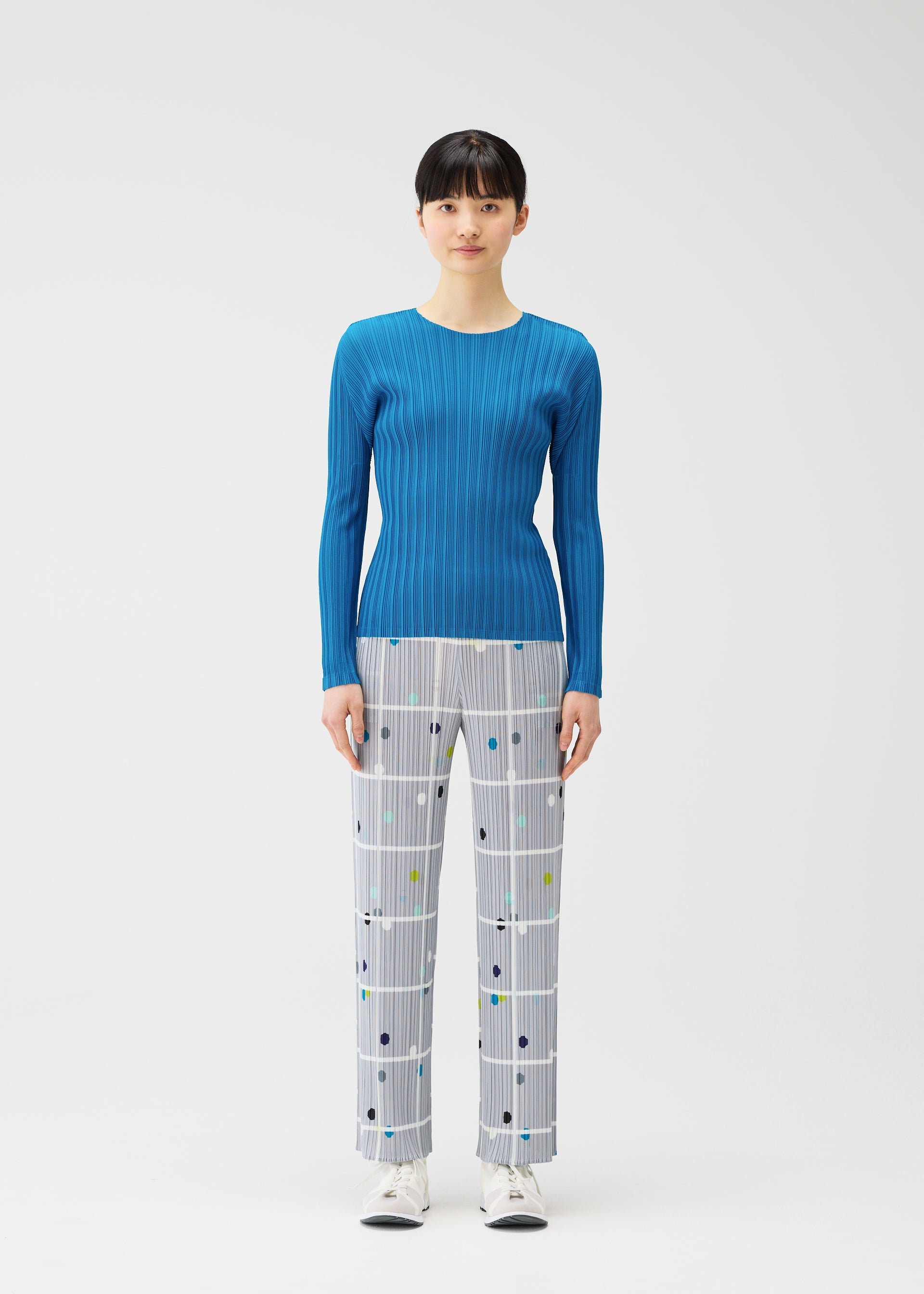 A model wears the PLEATS PLEASE ISSEY MIYAKE CROSSING DOTS trousers.