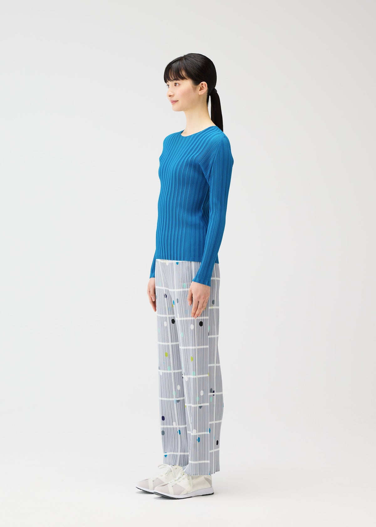 A model wears the PLEATS PLEASE ISSEY MIYAKE CROSSING DOTS trousers.