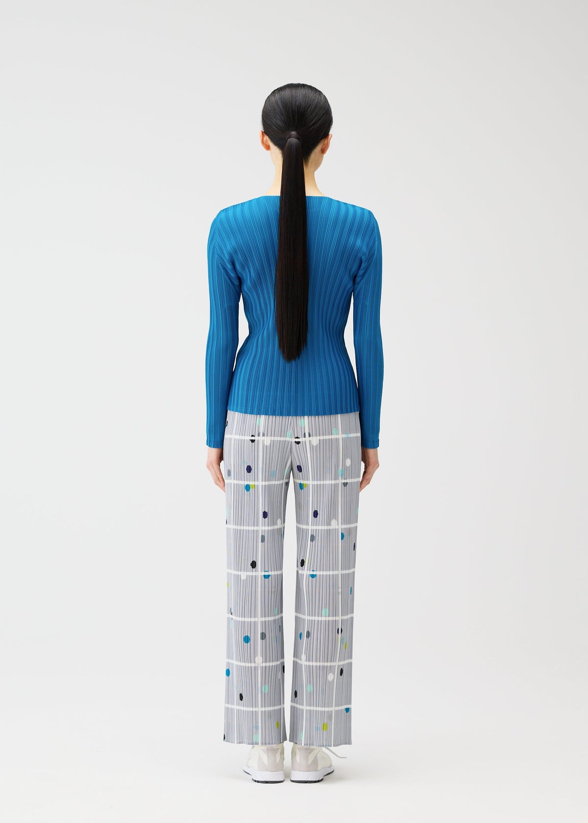A model wears the PLEATS PLEASE ISSEY MIYAKE CROSSING DOTS trousers.