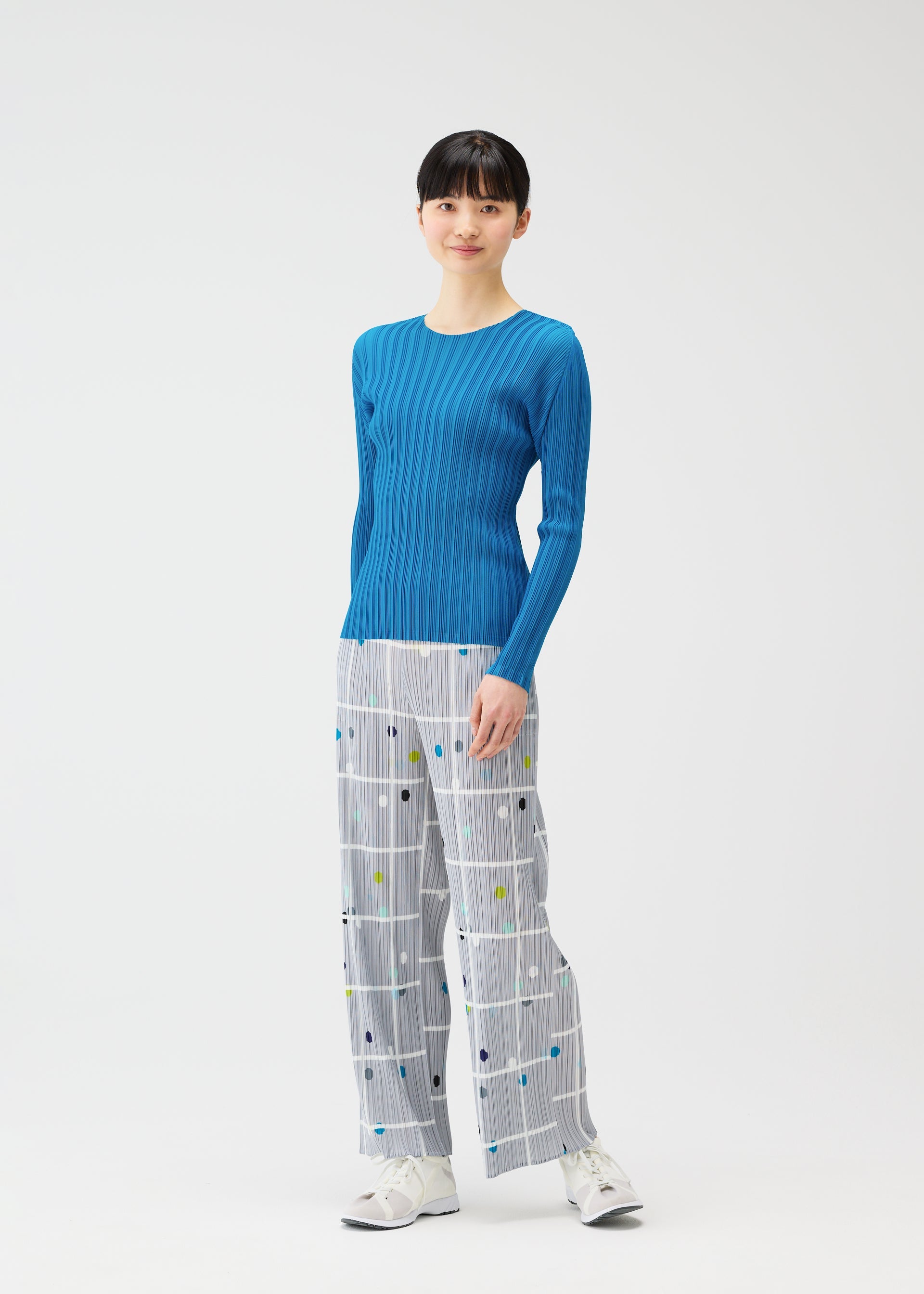 A model wears the PLEATS PLEASE ISSEY MIYAKE CROSSING DOTS trousers.