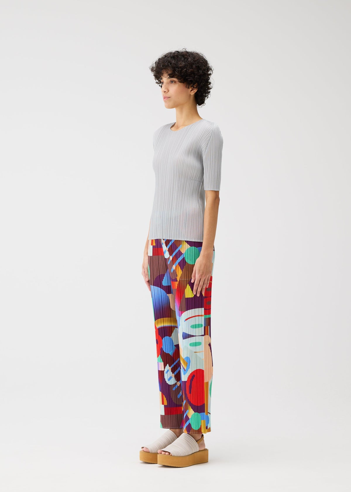 A model wears the PLEATS PLEASE ISSEY MIYAKE PLAYGROUND trousers.