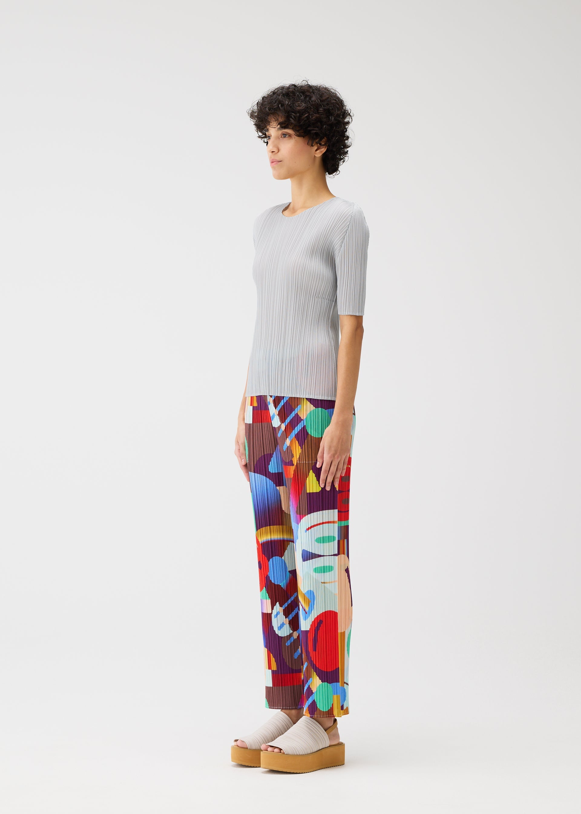 A model wears the PLEATS PLEASE ISSEY MIYAKE PLAYGROUND trousers.
