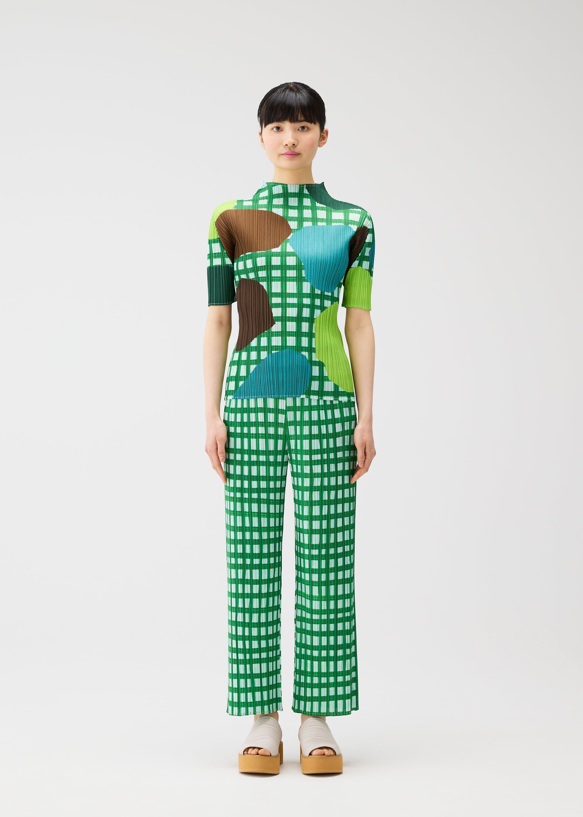 A model wears the PLEATS PLEASE ISSEY MIYAKE BASKET basket-trousers-green.