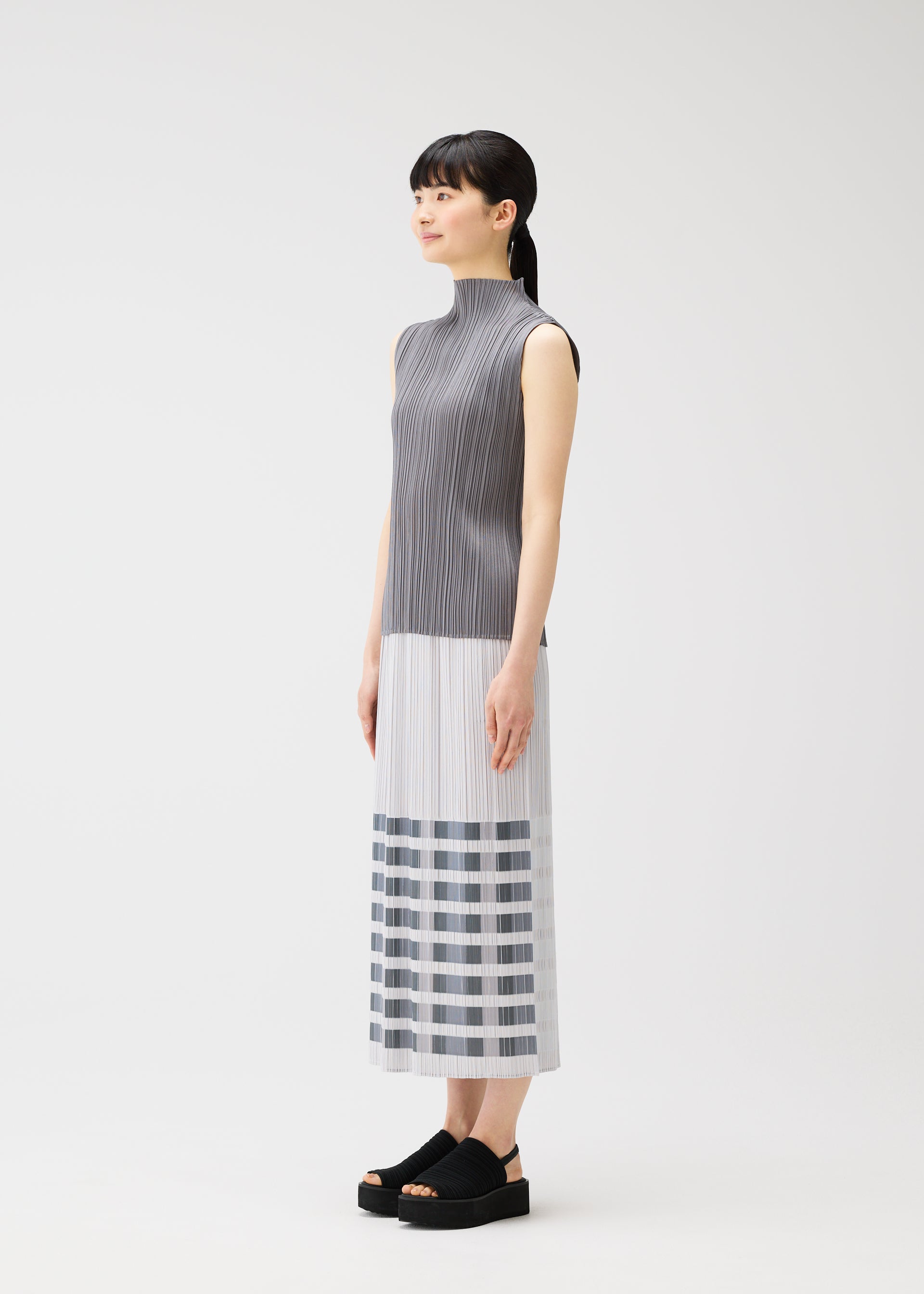 A model wears the PLEATS PLEASE ISSEY MIYAKE BUMPY BASKET bumpy-basket-skirt-charcoal.