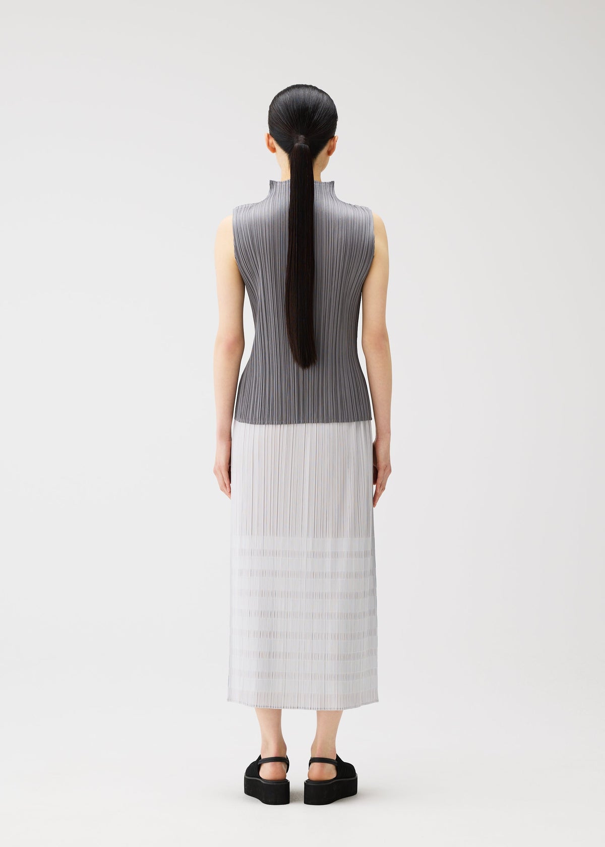 A model wears the PLEATS PLEASE ISSEY MIYAKE BUMPY BASKET bumpy-basket-skirt-green.