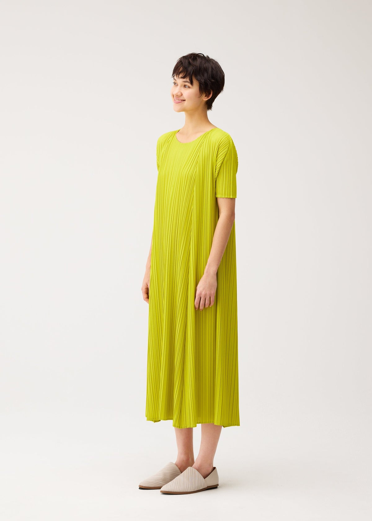 A model wears the PLEATS PLEASE ISSEY MIYAKE MELLOW PLEATS dress.