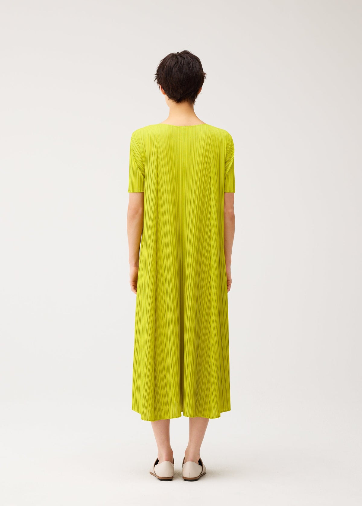 A model wears the PLEATS PLEASE ISSEY MIYAKE MELLOW PLEATS dress.