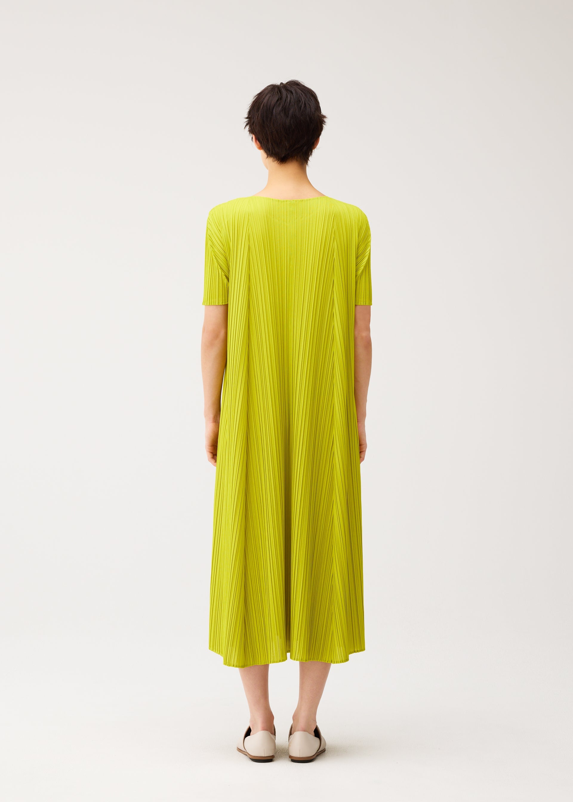A model wears the PLEATS PLEASE ISSEY MIYAKE MELLOW PLEATS dress.