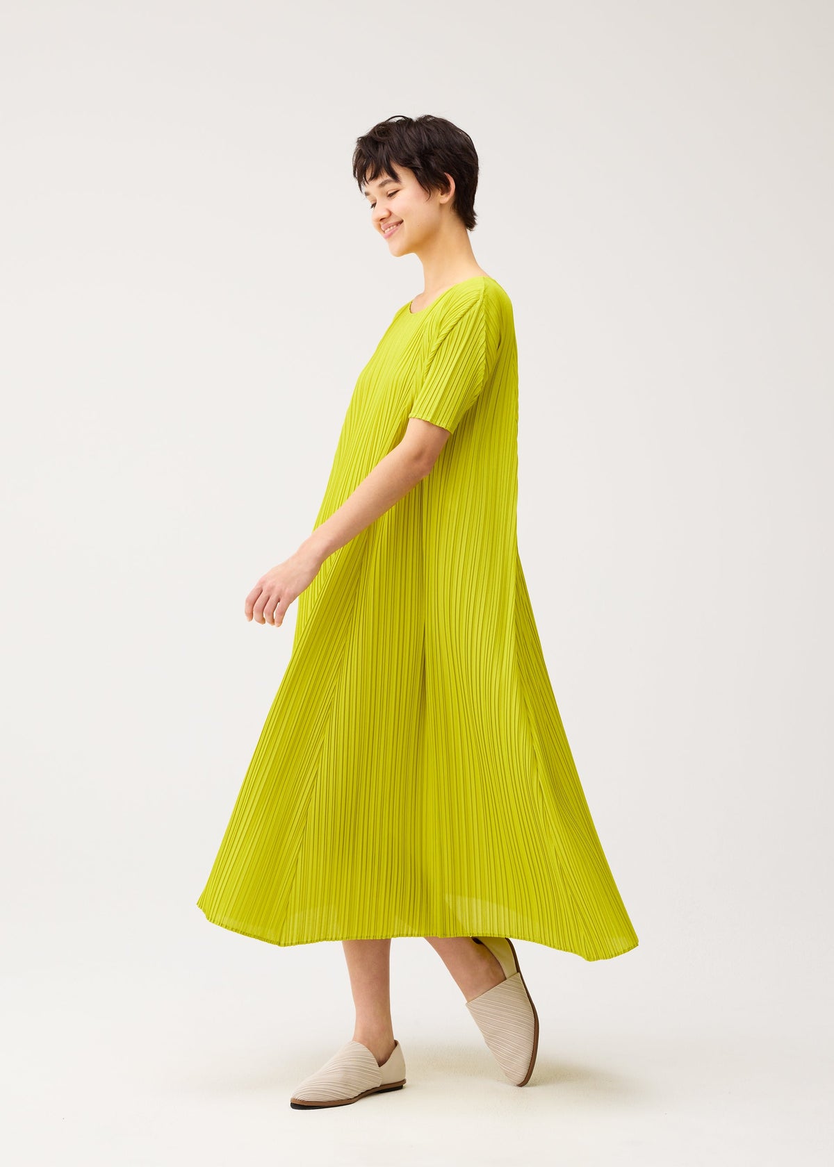 A model wears the PLEATS PLEASE ISSEY MIYAKE MELLOW PLEATS dress.