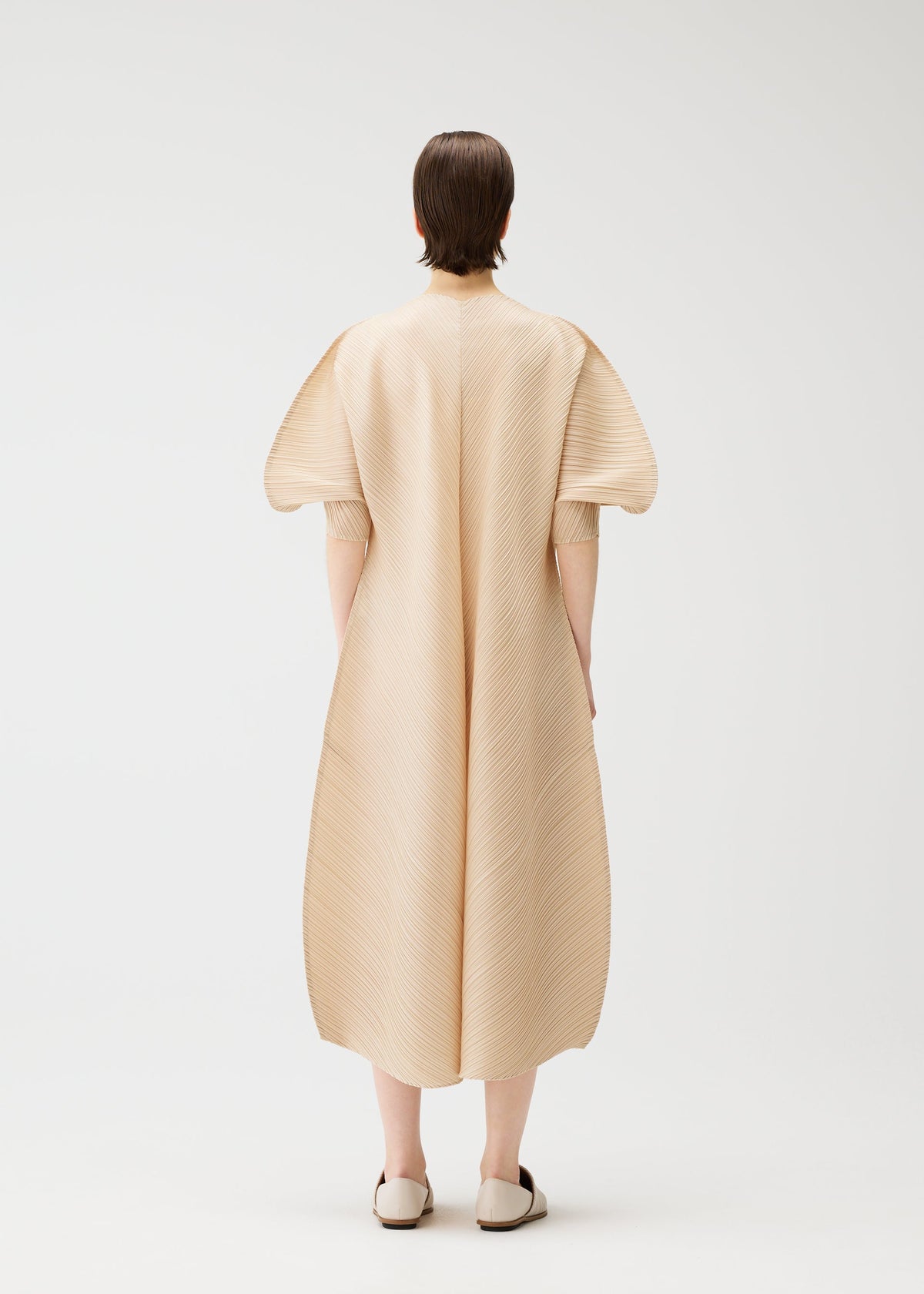 A model wears the PLEATS PLEASE ISSEY MIYAKE COAST dress.