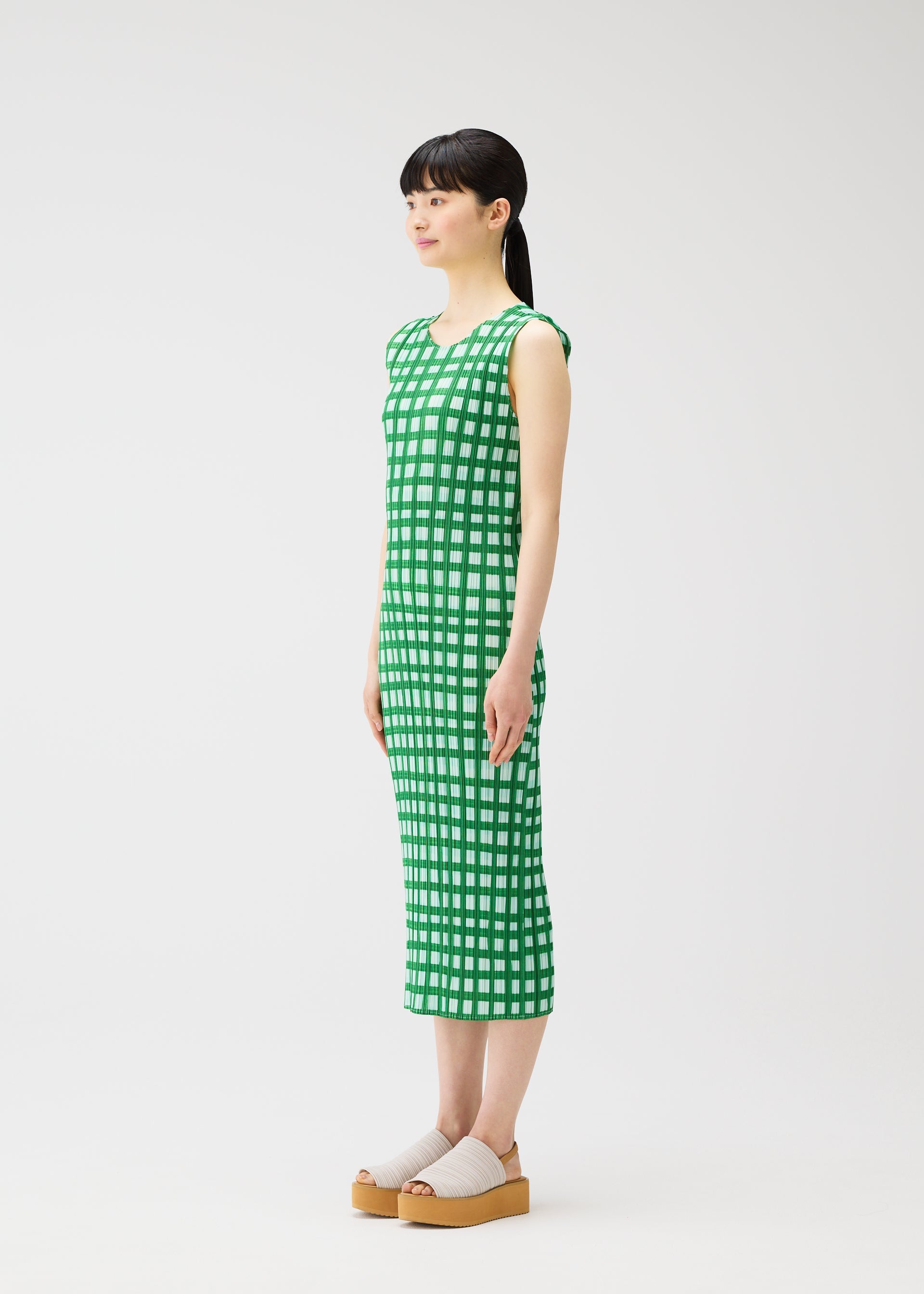 A model wears the PLEATS PLEASE ISSEY MIYAKE BASKET basket-dress-green.