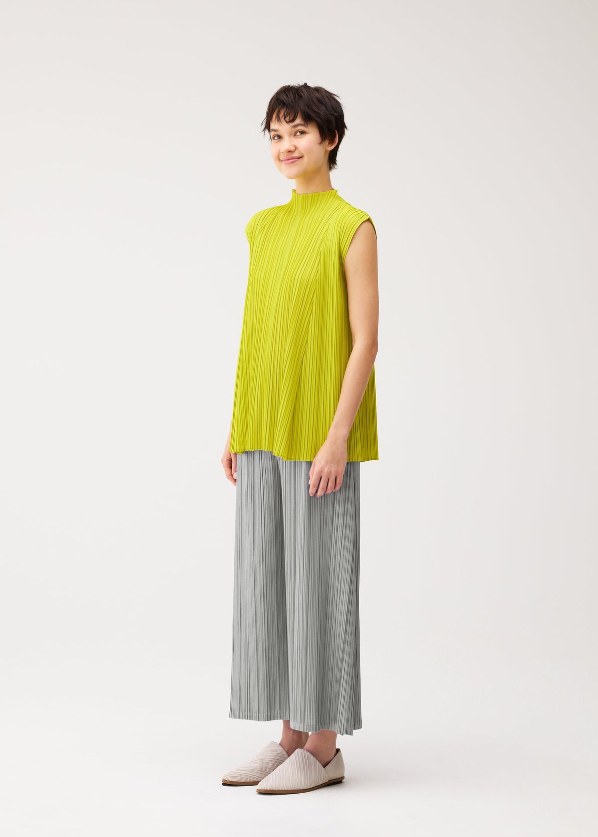 A model wears the PLEATS PLEASE ISSEY MIYAKE MELLOW PLEATS shirt.