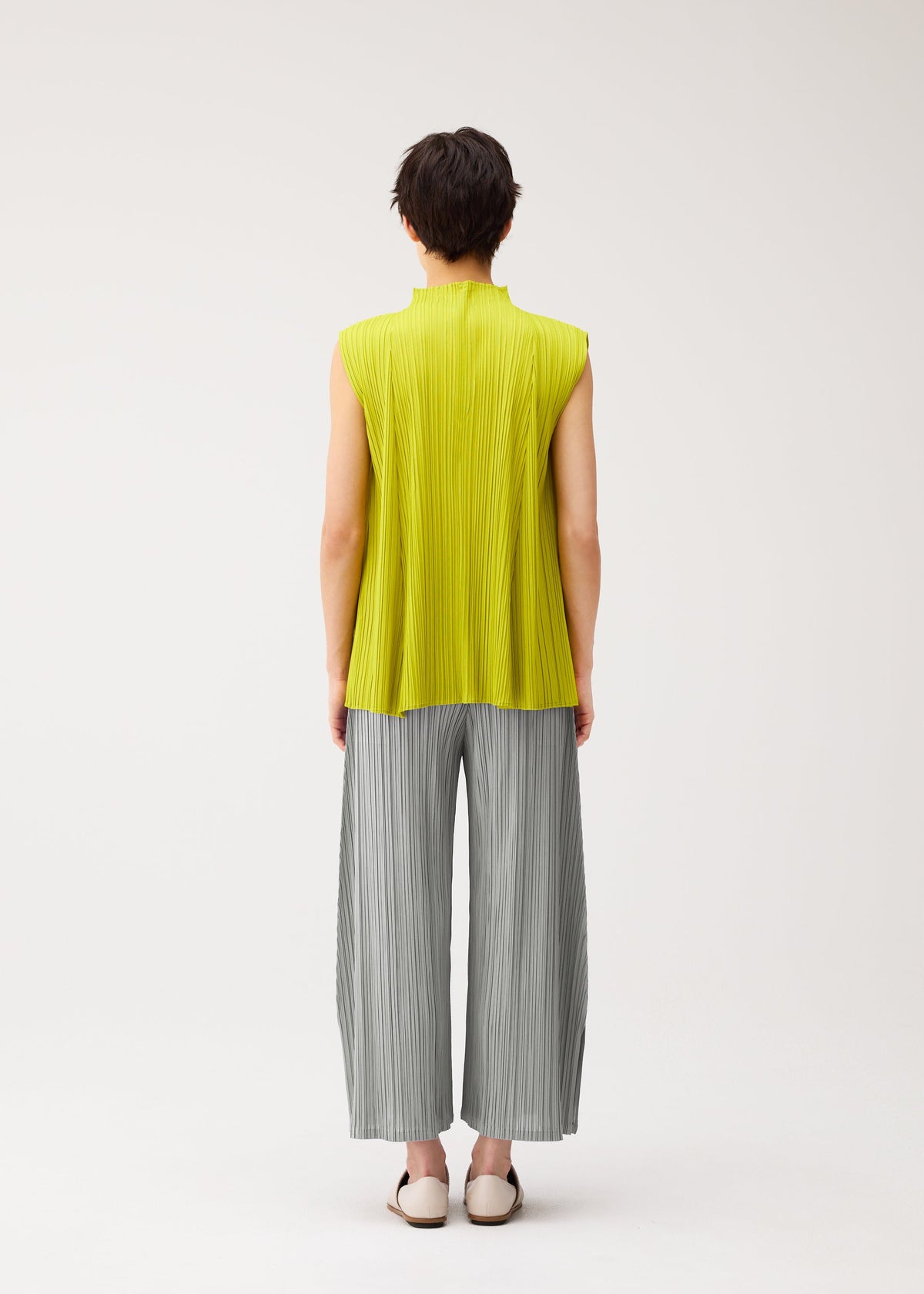 A model wears the PLEATS PLEASE ISSEY MIYAKE MELLOW PLEATS shirt.