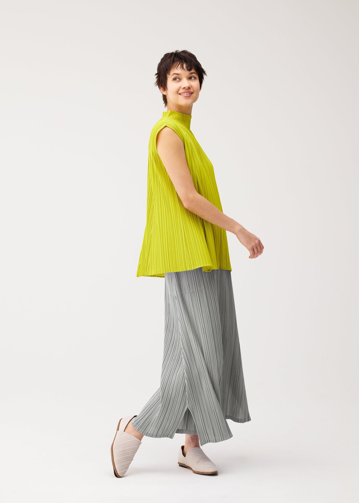 A model wears the PLEATS PLEASE ISSEY MIYAKE MELLOW PLEATS shirt.