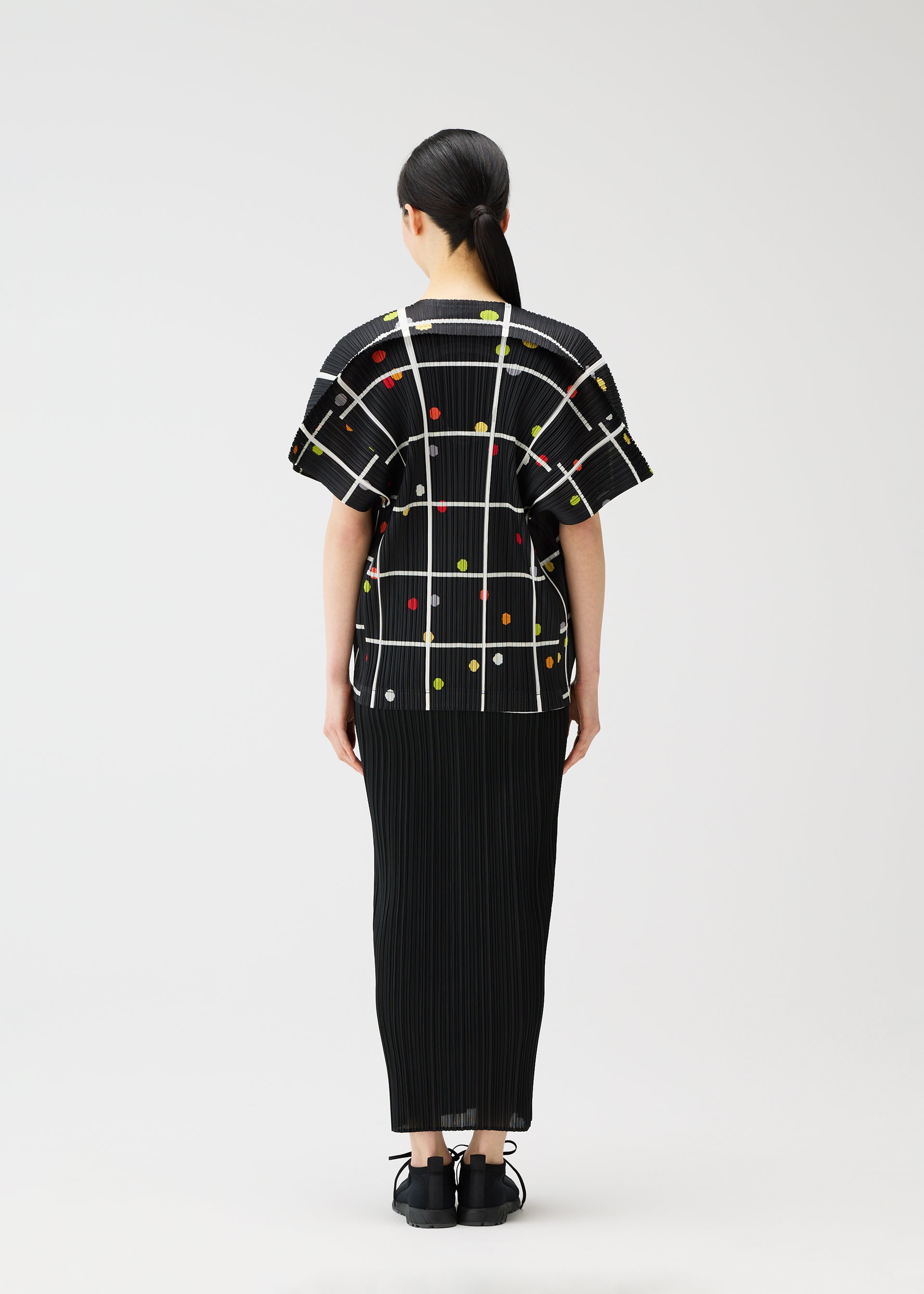 A model wears the PLEATS PLEASE ISSEY MIYAKE CROSSING DOTS shirt.