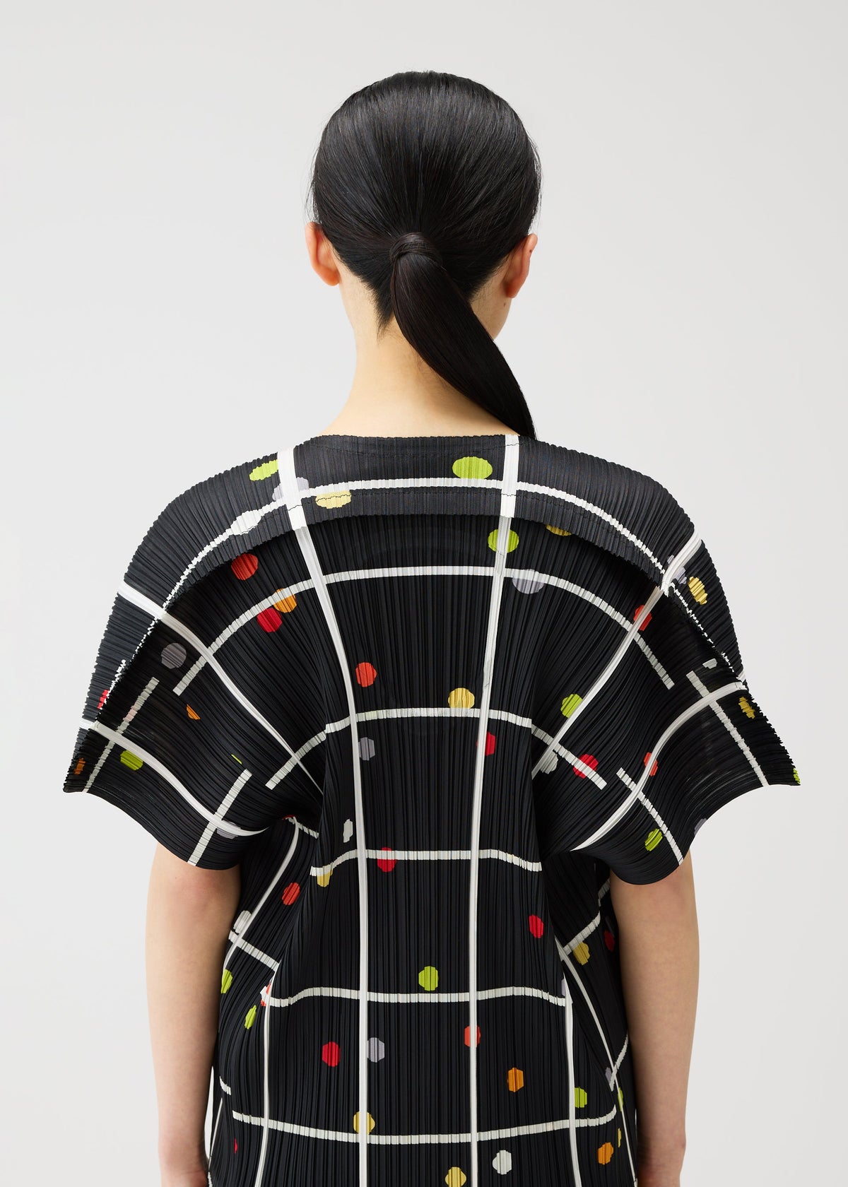 A model wears the PLEATS PLEASE ISSEY MIYAKE CROSSING DOTS shirt.