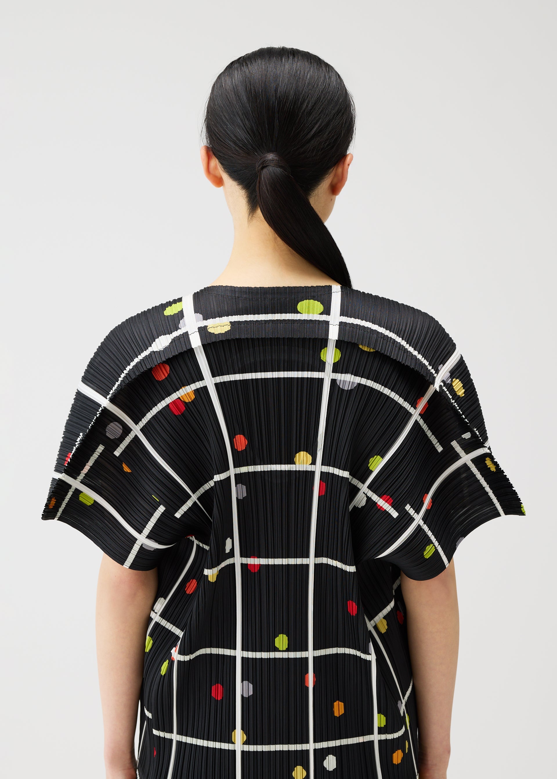 A model wears the PLEATS PLEASE ISSEY MIYAKE CROSSING DOTS shirt.